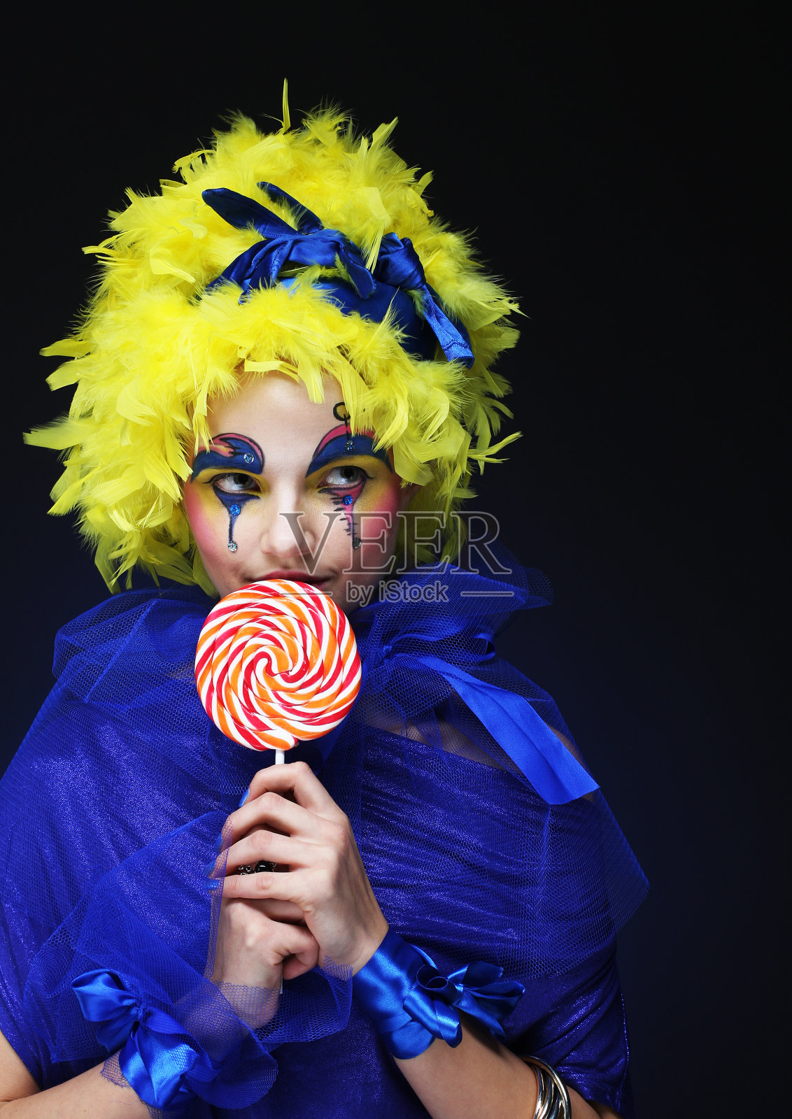 带着棒棒糖的年轻女子。和狂欢节。明亮的假发照片摄影图片