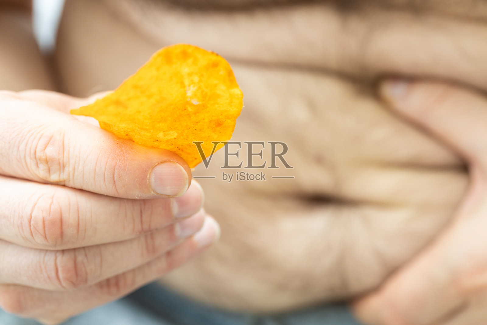 超重问题，一只手拿着胖肚子，另一只手拿着薯条，概念，肥胖，过量摄入饱和脂肪照片摄影图片