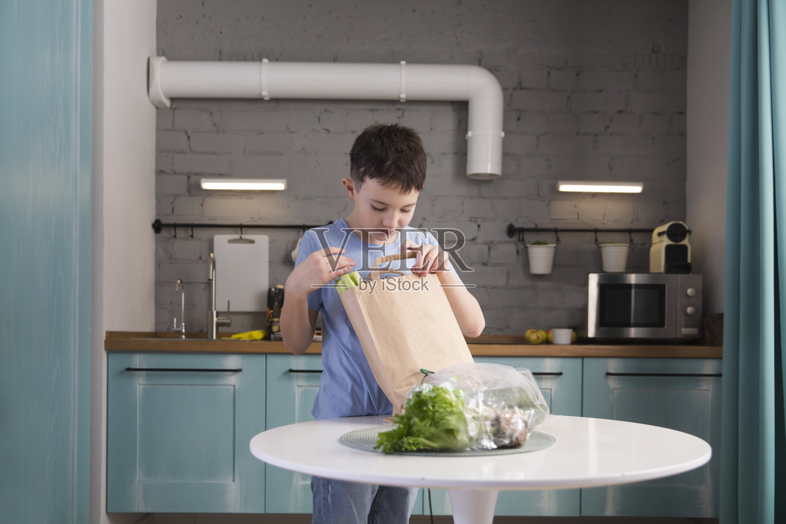 一个少年在家里的厨房里拆开装着食物的包装。产品交付。健康营养照片摄影图片