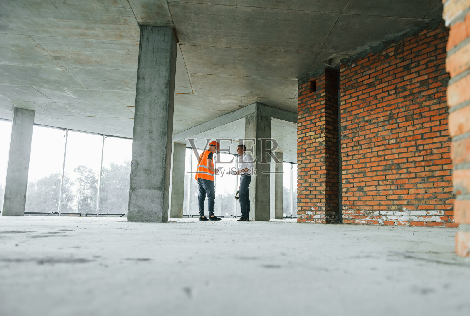 遥远的视图。穿西装的人和穿橙色防护服的勤杂工正在施工照片摄影图片