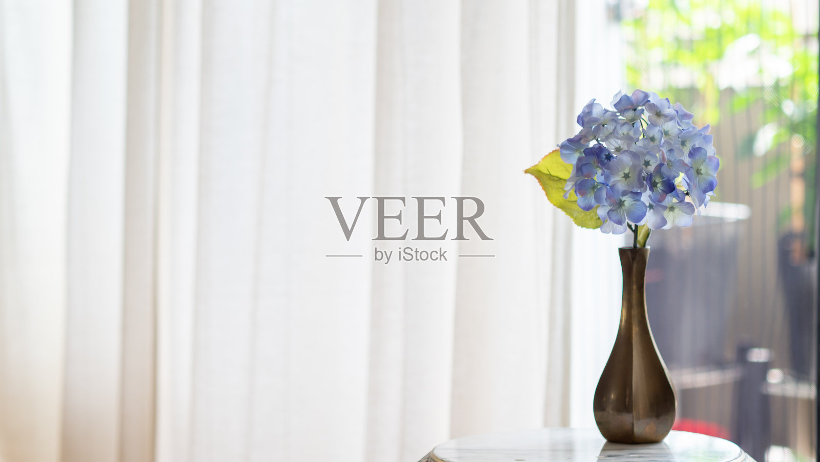 在一个阳光明媚的春日，半透明的花瓶里插着粉红色的花朵。照片摄影图片