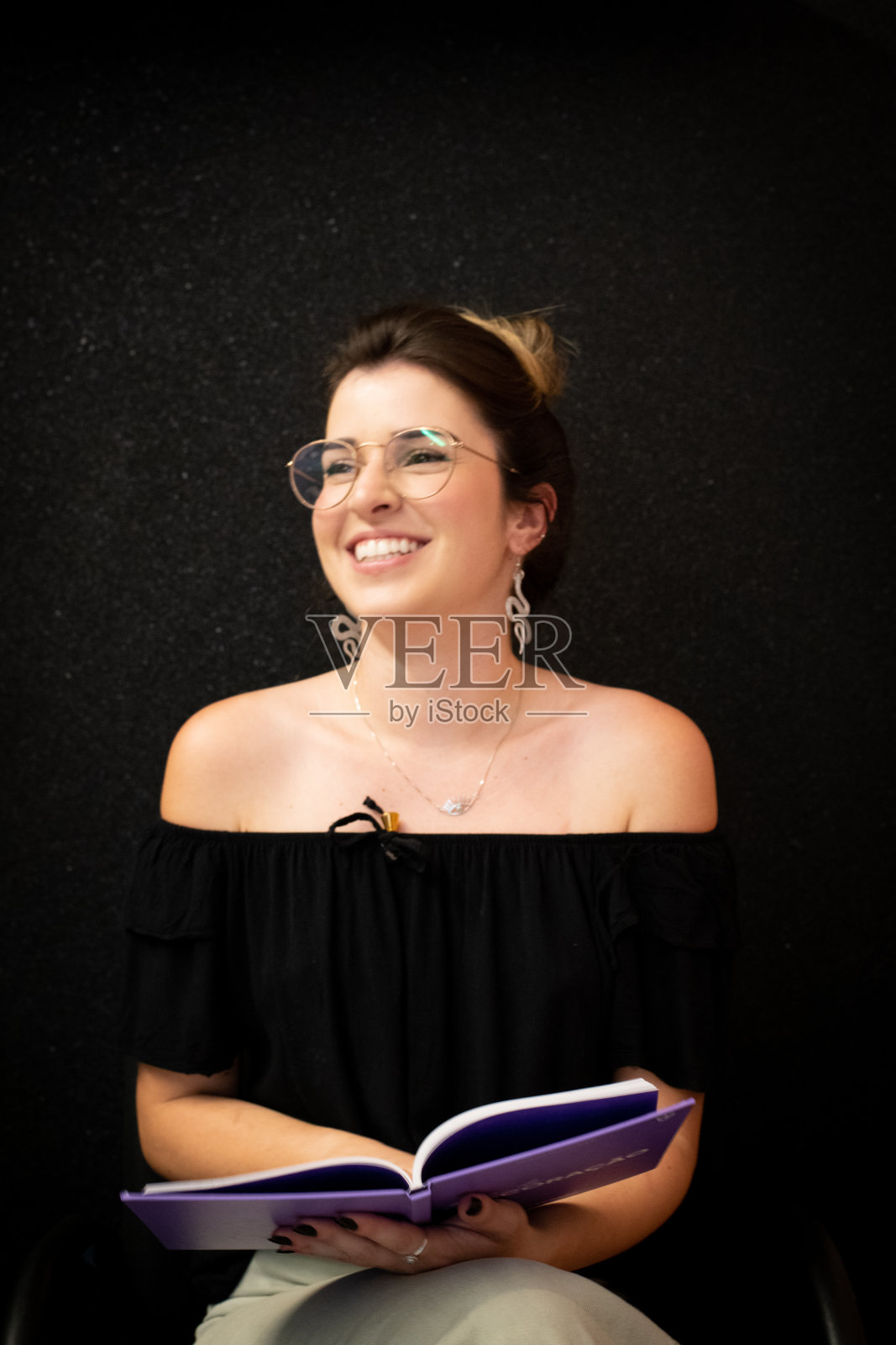 一个微笑着拿着一本书的年轻女人的肖像照片摄影图片