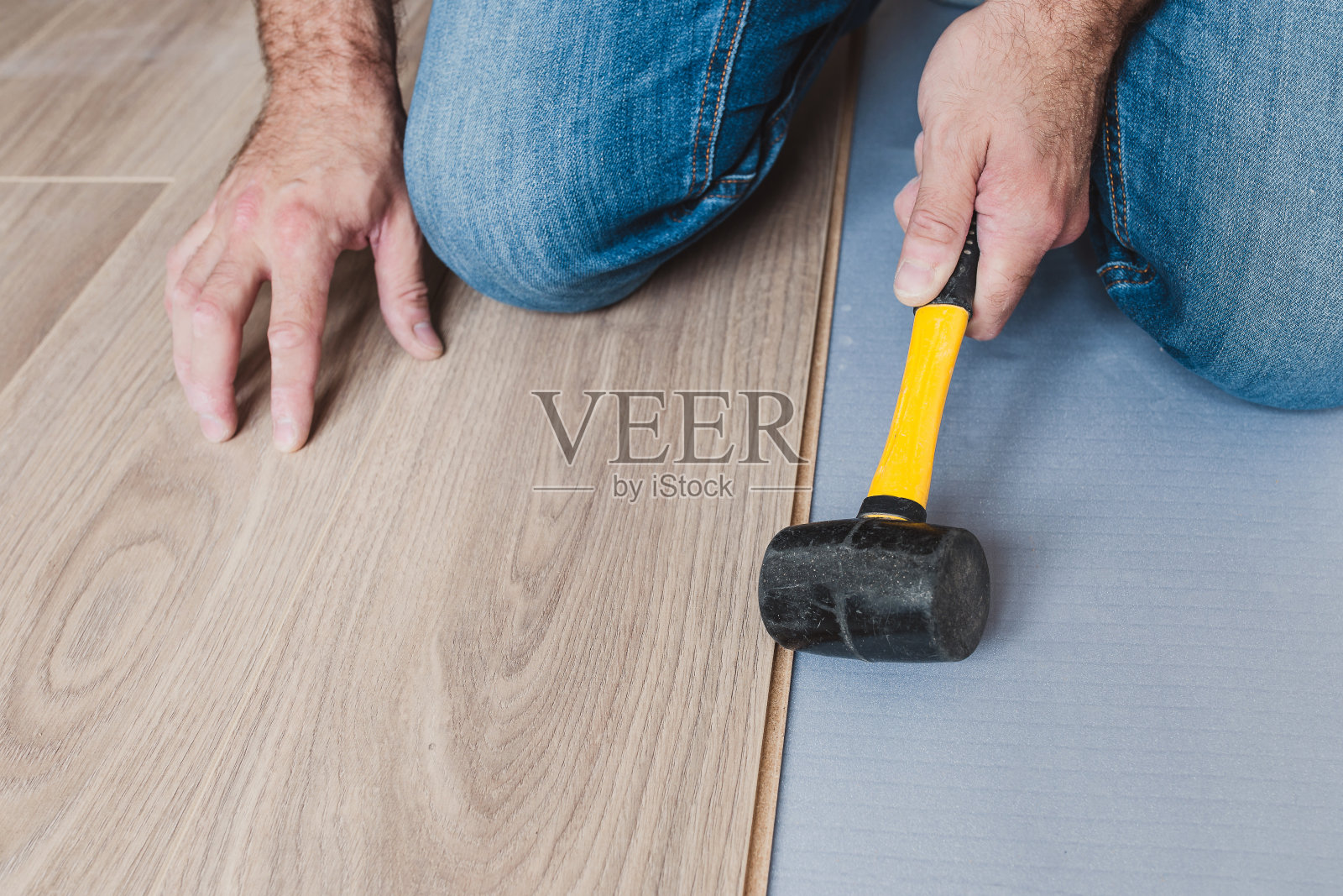 不正确的层压板安装-工头用锤子打面板的边缘照片摄影图片