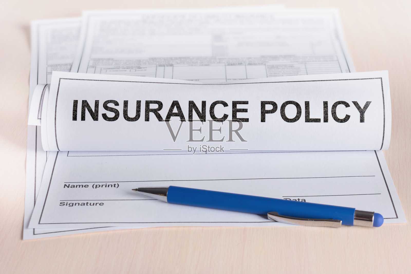 保险的概念。卷起保险单和一支笔放在桌上。照片摄影图片
