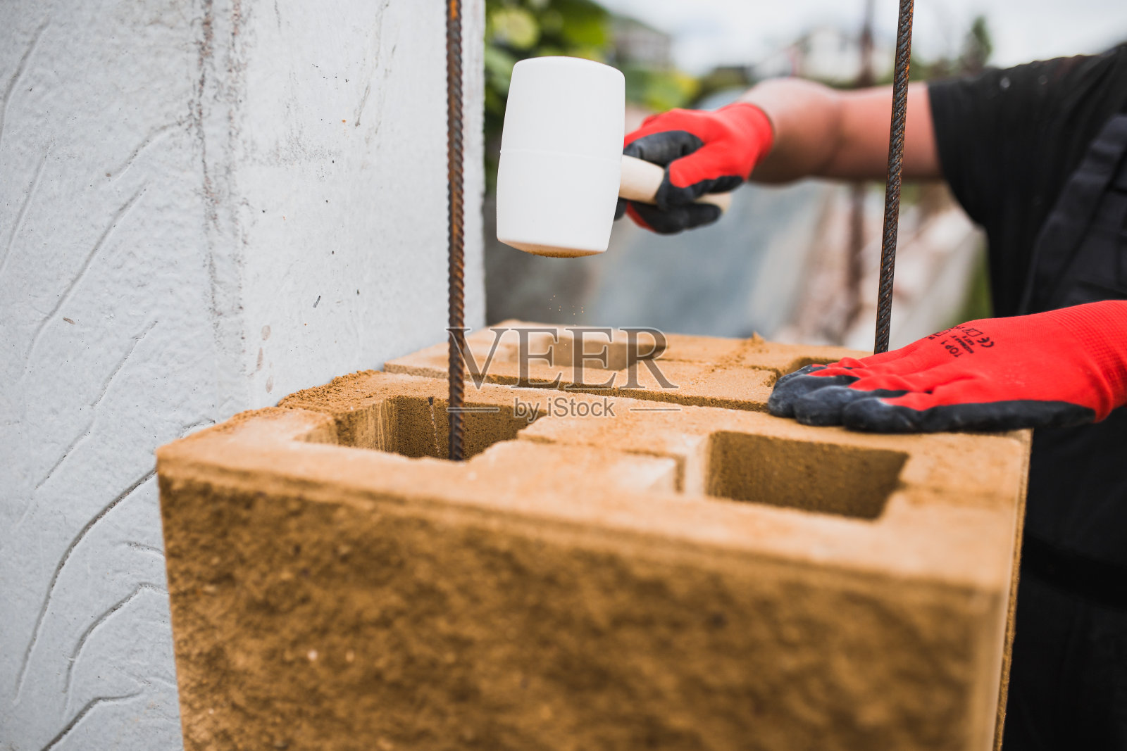 一个专业的砖匠用水泥块为石头栅栏建造柱子照片摄影图片