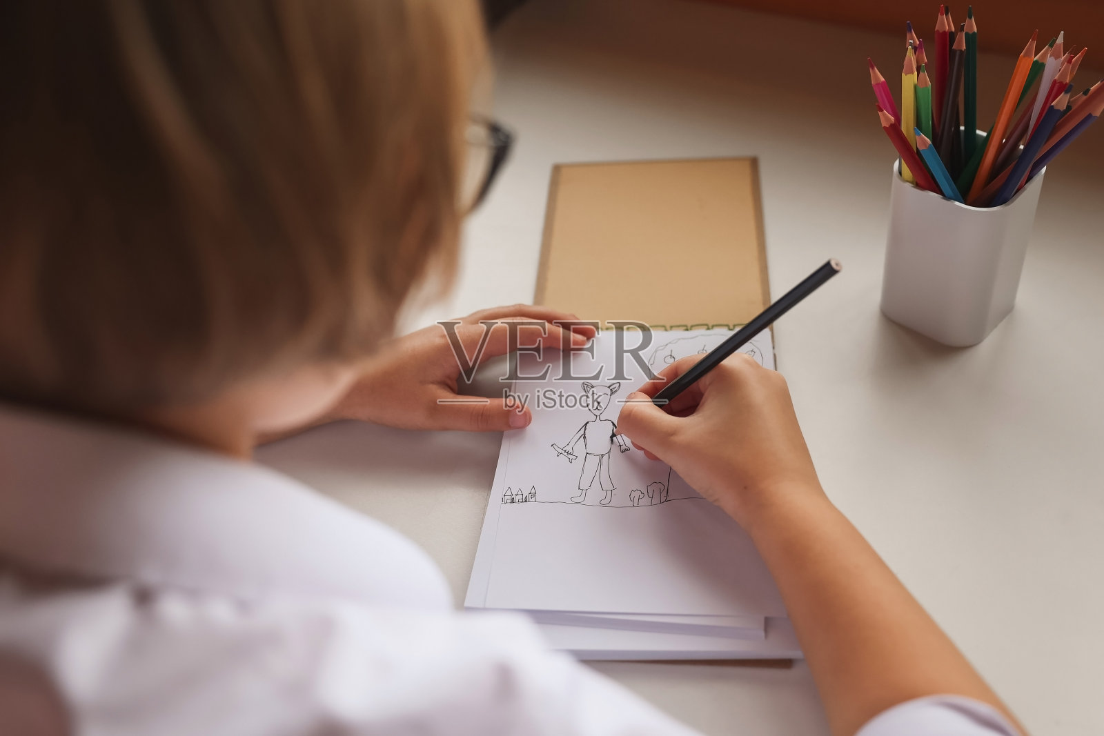 一名女学生坐在室内的桌子旁做作业。女孩在家做作业。远程学习。课,作业,教育。照片摄影图片