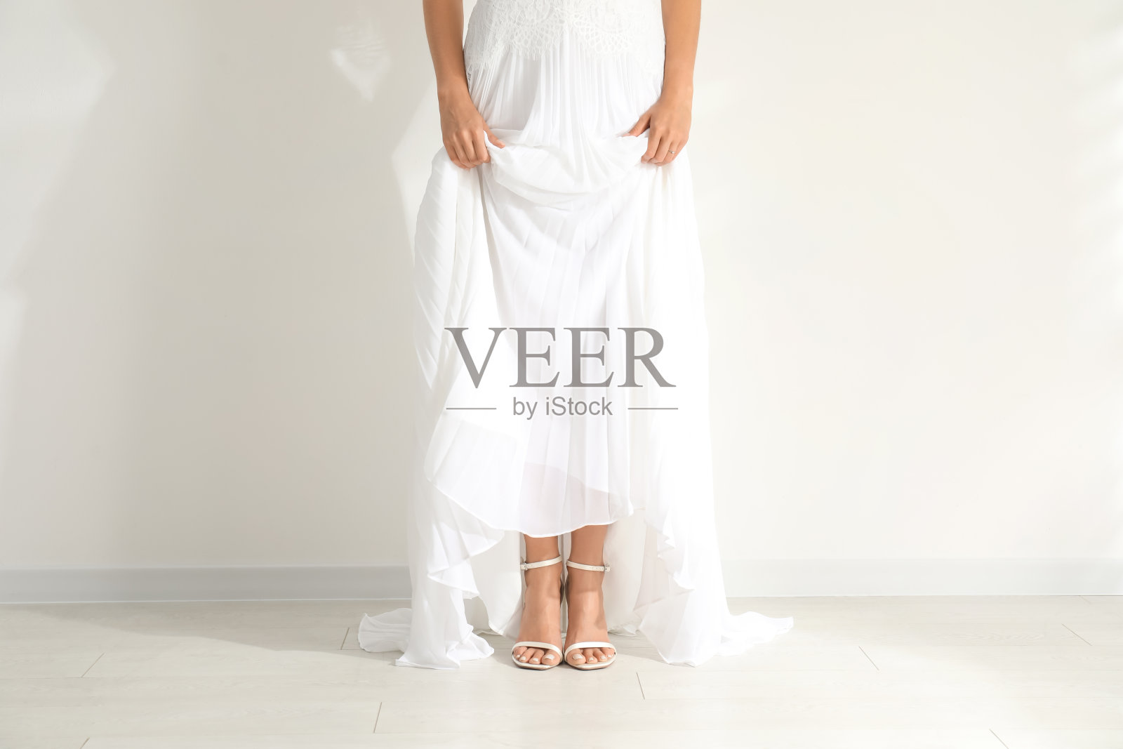 年轻的新娘穿着美丽的婚纱近光墙，特写照片摄影图片