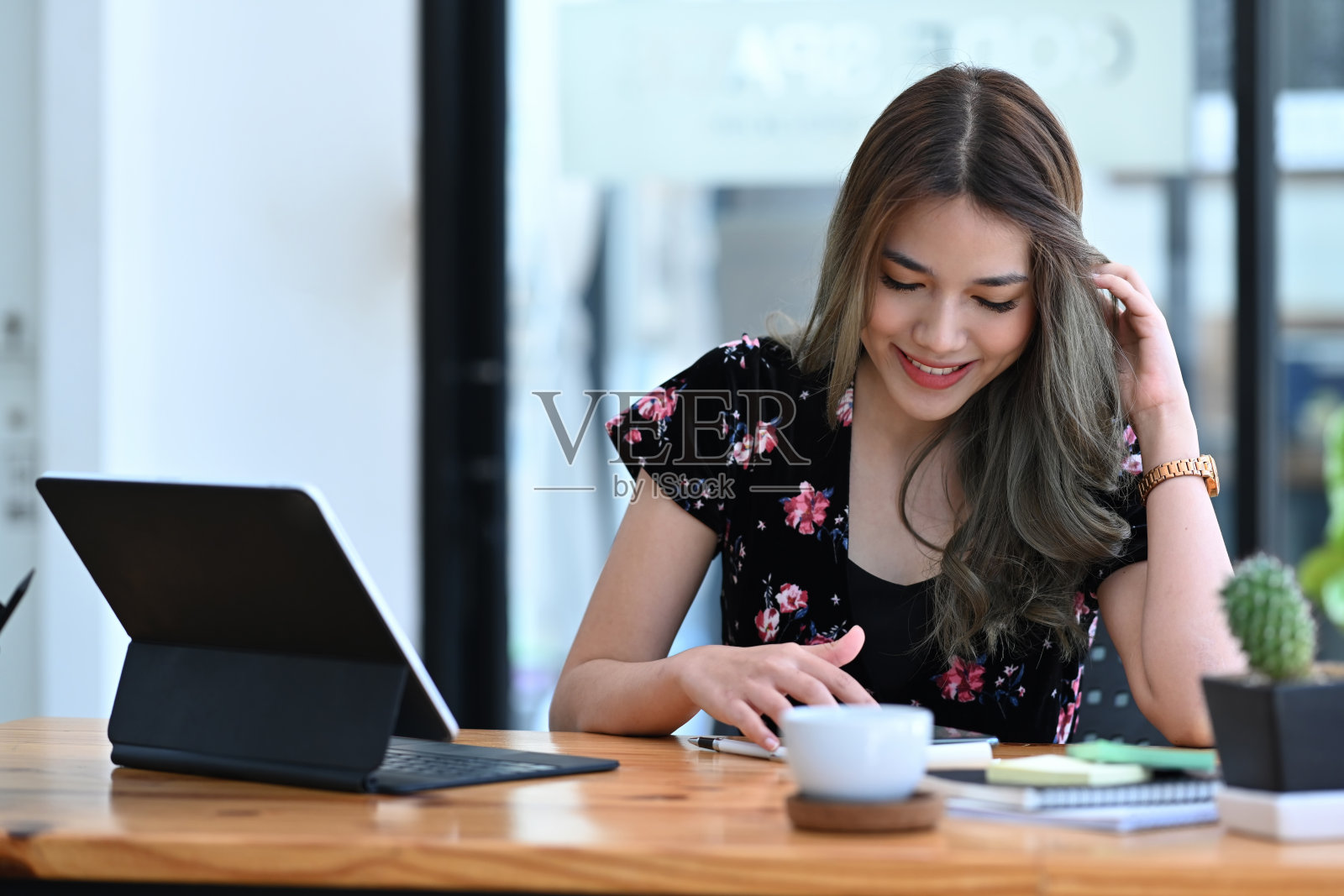 开朗的年轻女性自由职业者，工作时使用电脑桌面和智能手机。照片摄影图片