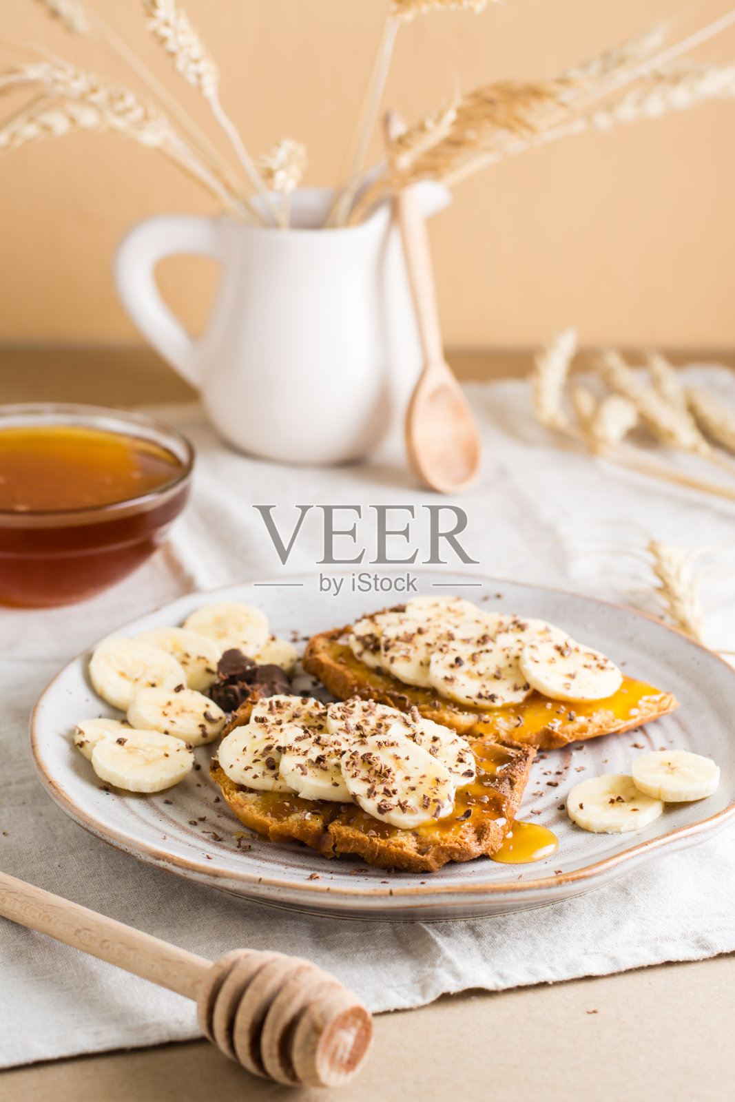 准备吃桌上盘子里的蜂蜜、香蕉和巧克力三明治。自制素食点心。俯视图照片摄影图片