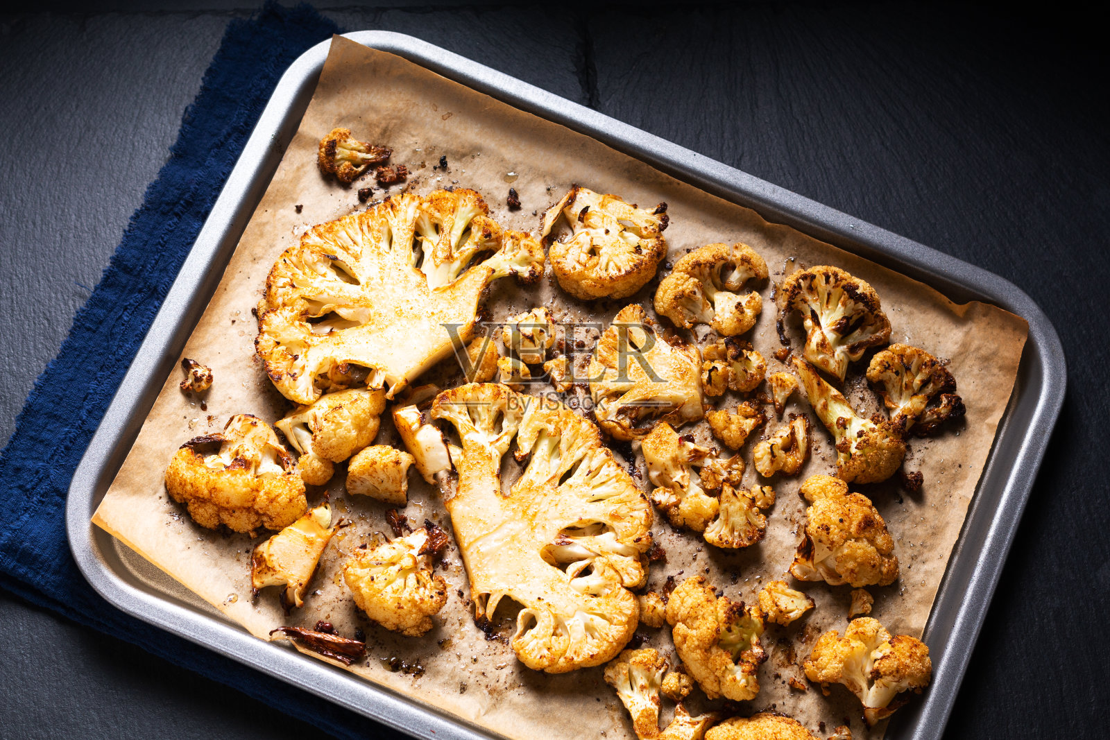 食品概念烤有机花椰菜在烤盘上的黑色石板石背景与复制空间照片摄影图片