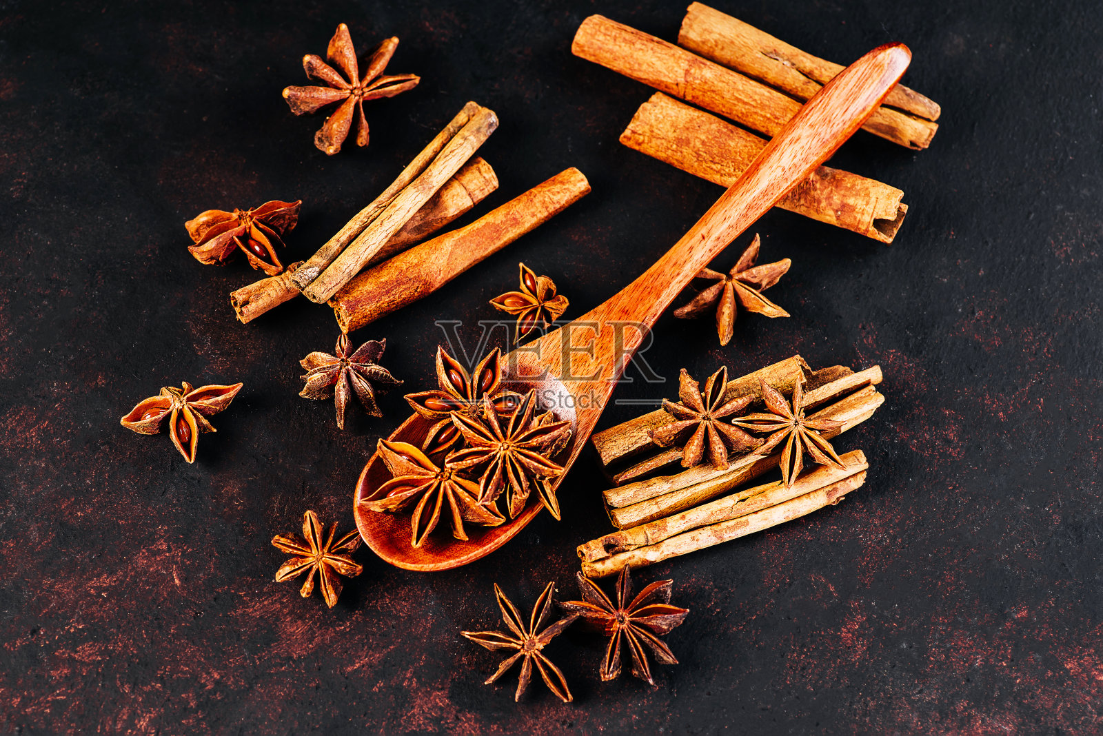 加香料的热葡萄酒。副本的空间。圣诞家居装饰。新年贺卡的背景。肉桂棒配八角茴香和橙子干，为秋冬暖饮做准备，背景为黑色。圣诞物品放在木桌上。照片摄影图片