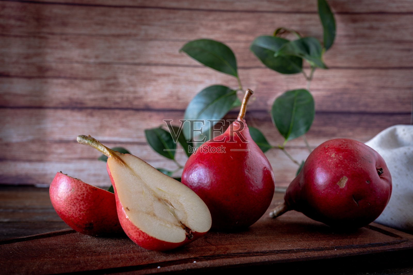 一个红梨切成两半，其他多汁的红战梨放在板上。有机和天然产品。照片摄影图片