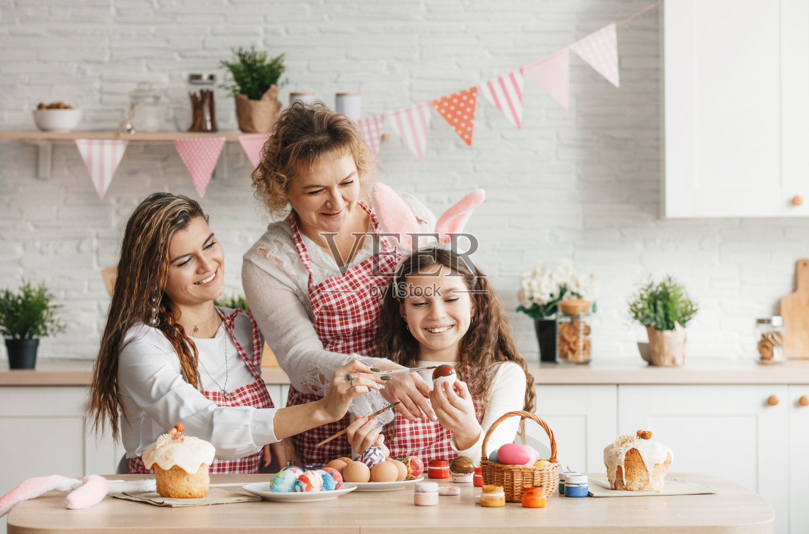 一位快乐的母亲和她的成年女儿在家里的厨房里画复活节彩蛋。照片摄影图片