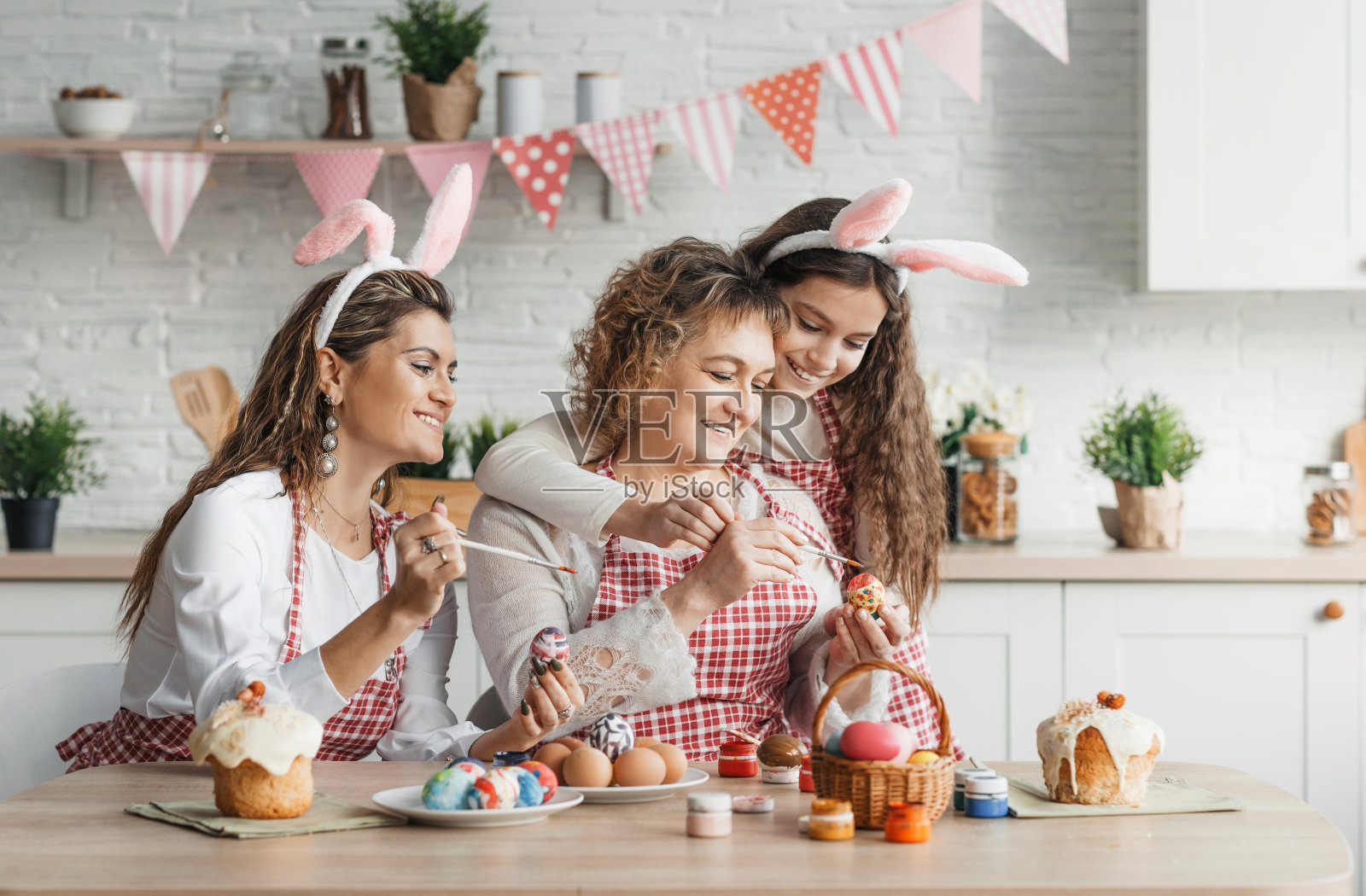 一位快乐的母亲和她的成年女儿在家里的厨房里画复活节彩蛋。照片摄影图片