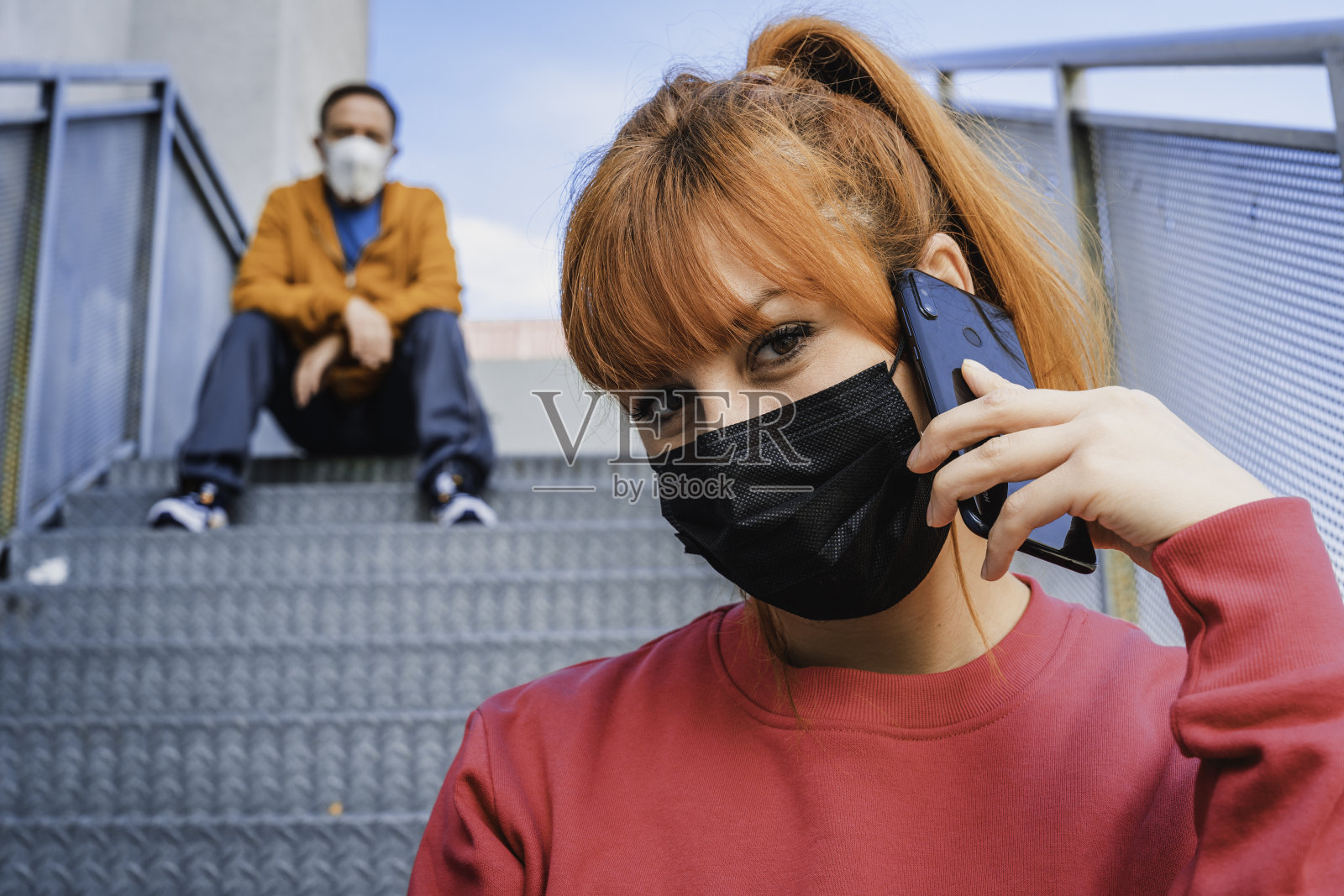 一个年轻女人和一个坐在楼梯上的男人通电话的特写镜头照片摄影图片