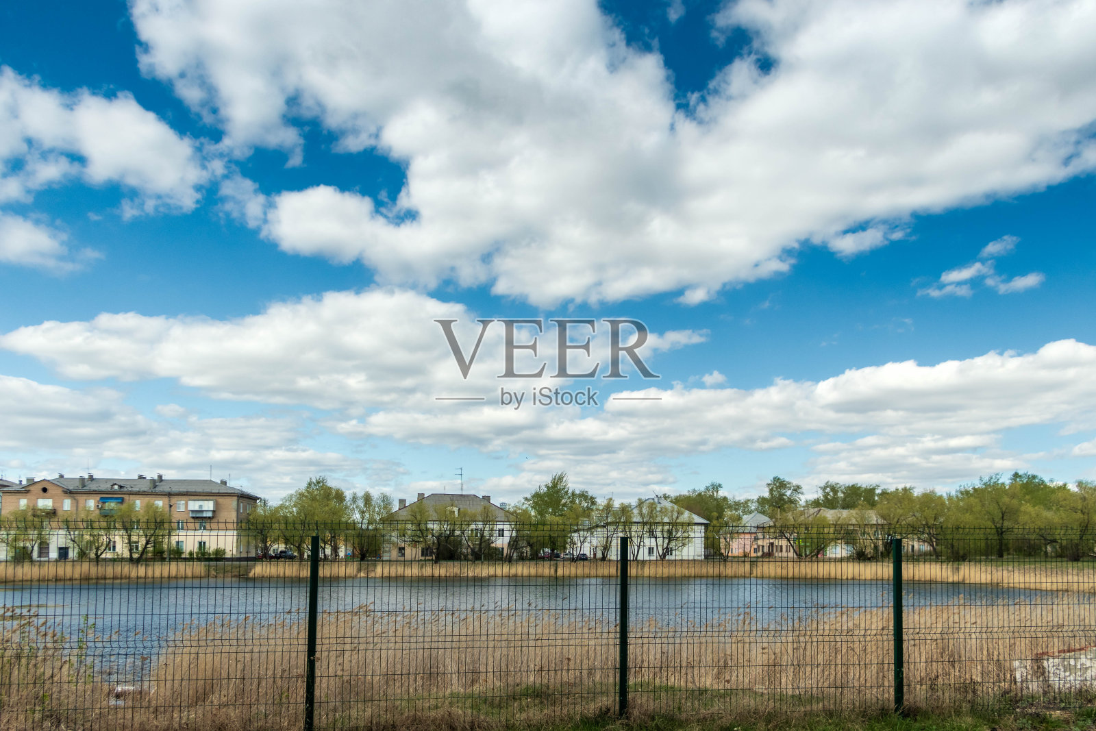 有一个湖后面的金属栅栏，一个阴天。照片摄影图片