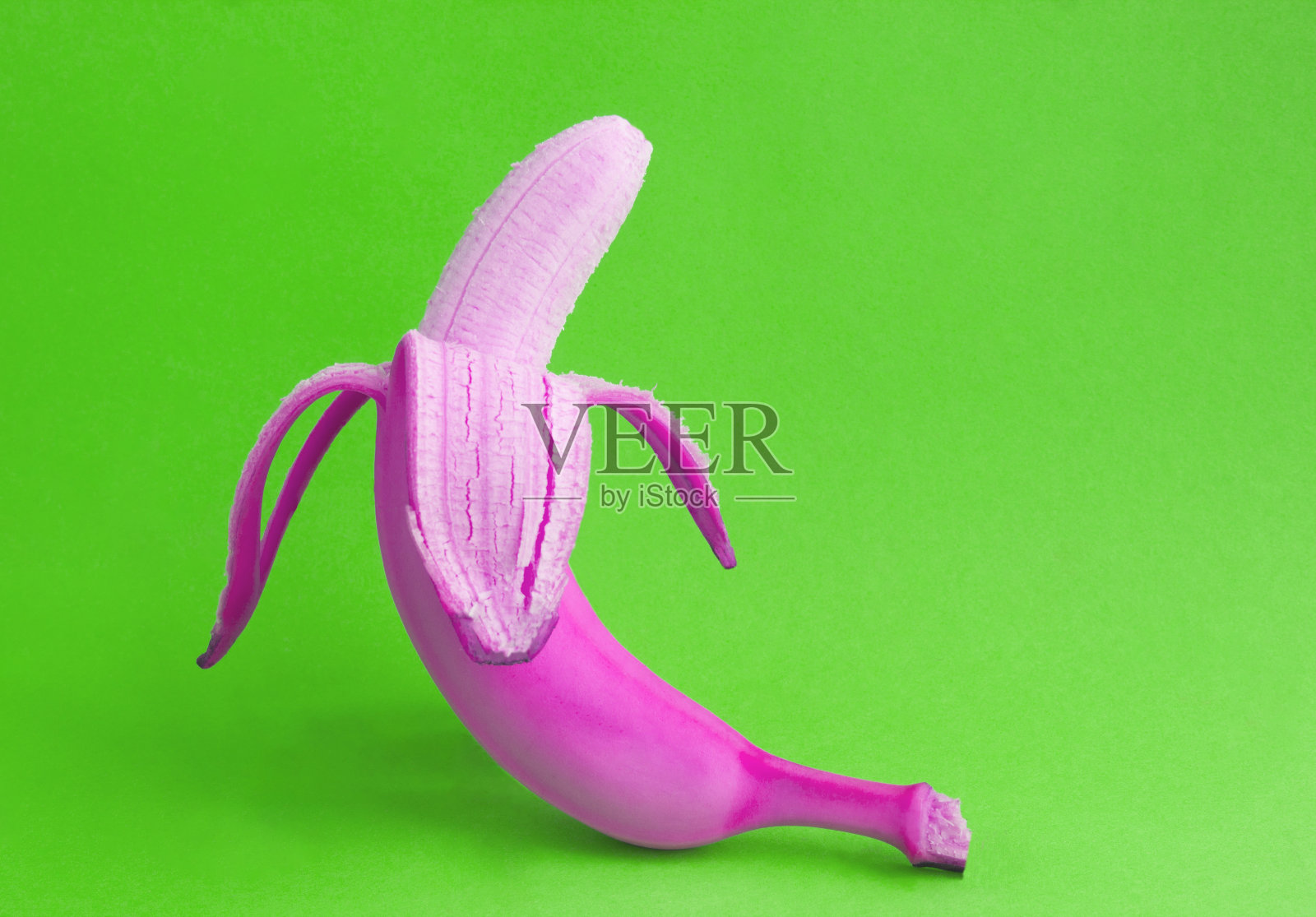 在绿色背景上的粉红色剥皮香蕉的特写。副本的空间。照片摄影图片
