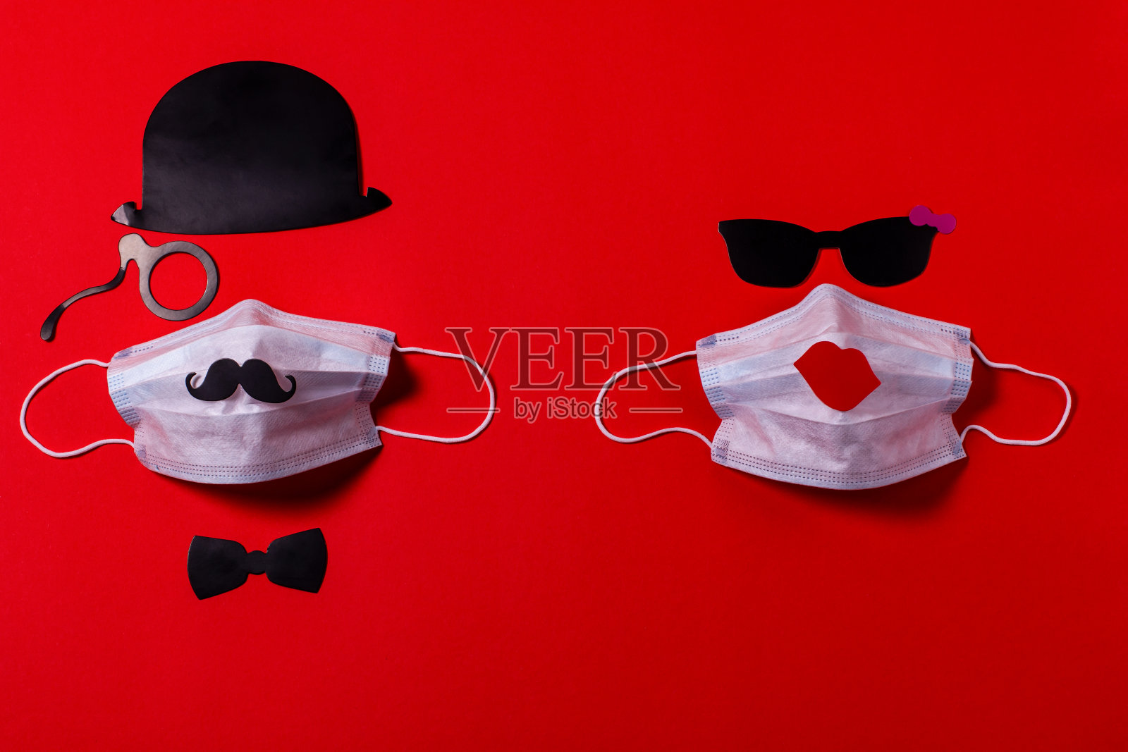 友谊病毒防护。带眼镜的医用口罩，由硬纸板制成，背景是红色的纹理纸。照片摄影图片