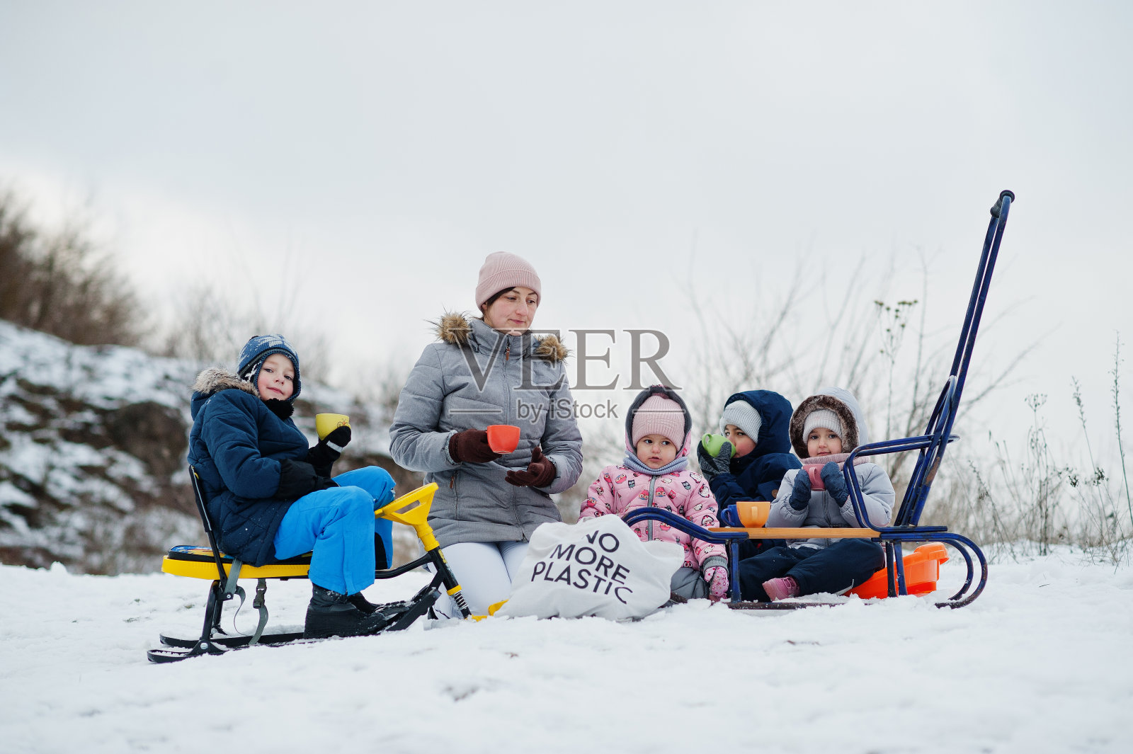 冬天，一家人在户外玩雪橇，孩子们在玩耍，喝茶。照片摄影图片
