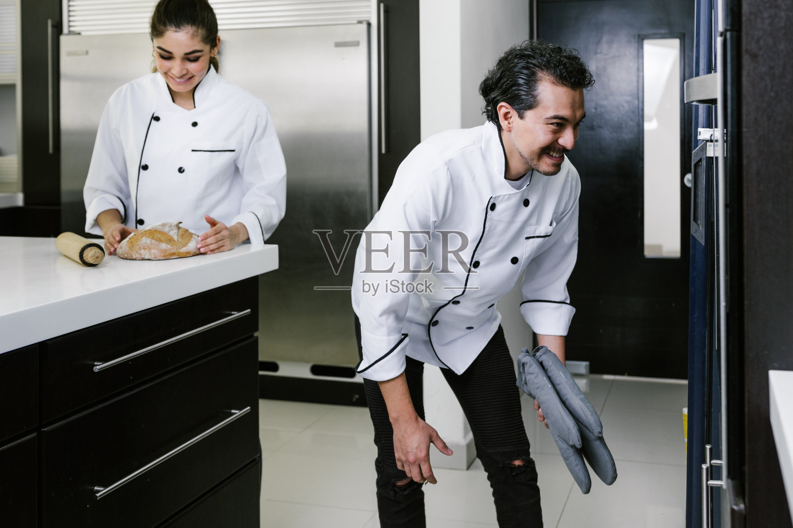 拉丁美洲的墨西哥，一名年轻的拉丁男子在厨房的烤箱上烤面包照片摄影图片