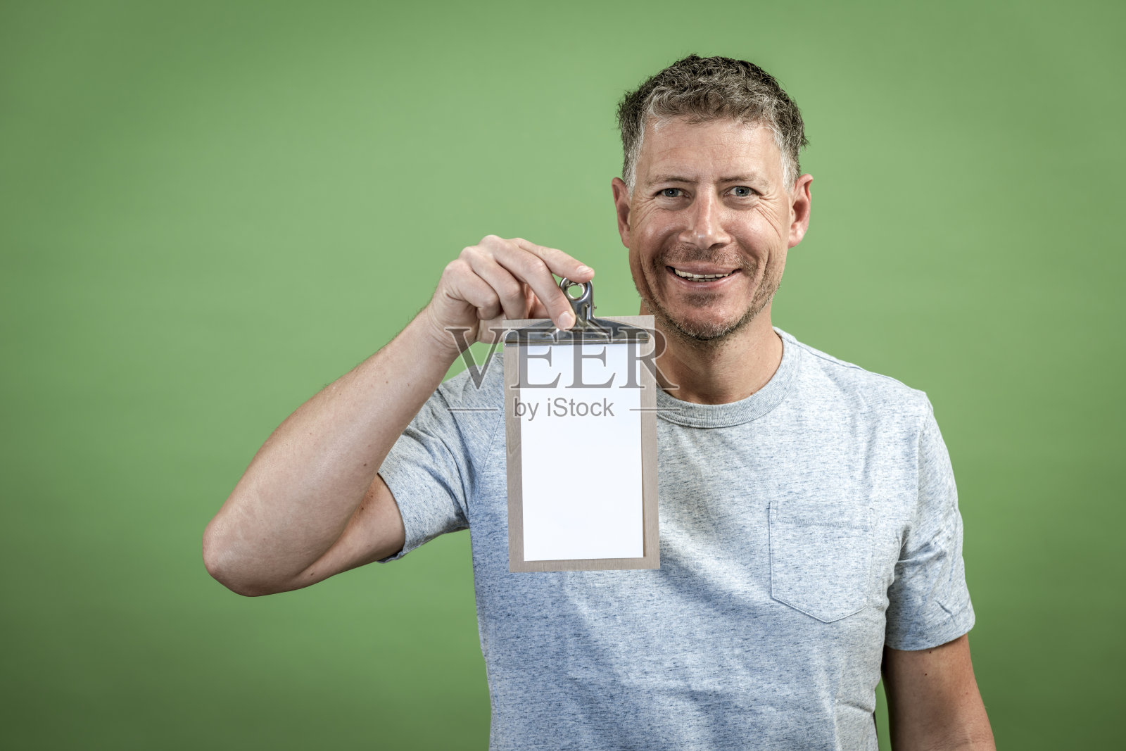 一个人拿着剪贴板在绿色背景前面照片摄影图片