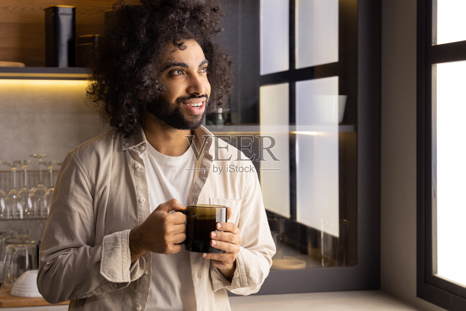 穆斯林男子喜欢站在厨房的窗户边喝热茶照片摄影图片