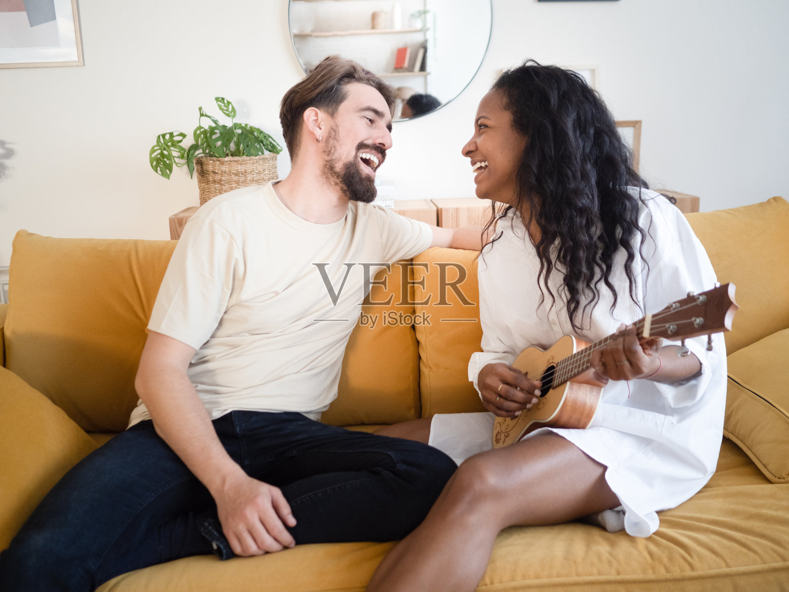 幸福的多民族年轻夫妇坐在家里的沙发上唱着歌照片摄影图片