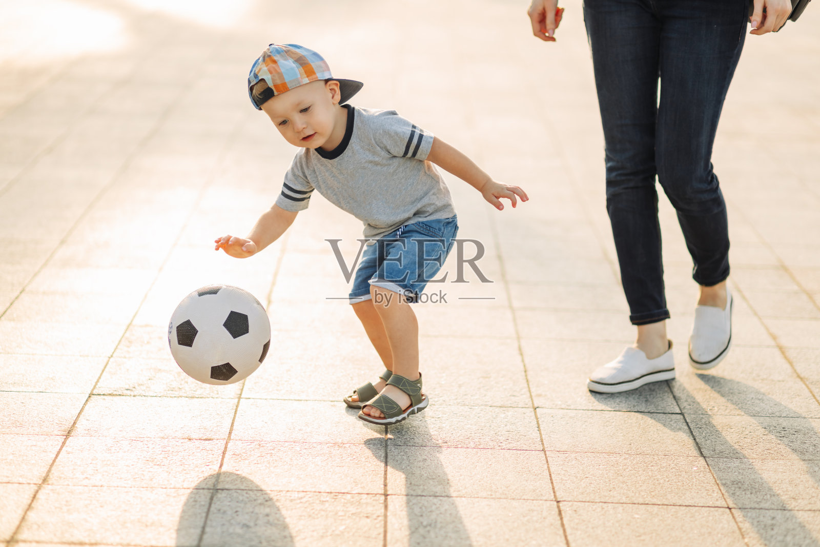 妈妈和儿子一起在公园里踢足球，小男孩踢足球，孩子学习踢足球照片摄影图片