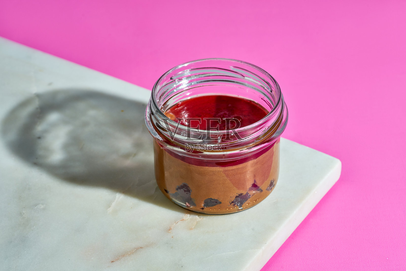 樱桃巧克力蛋奶酥?在一个玻璃罐里，在一个粉红色背景的大理石板上照片摄影图片