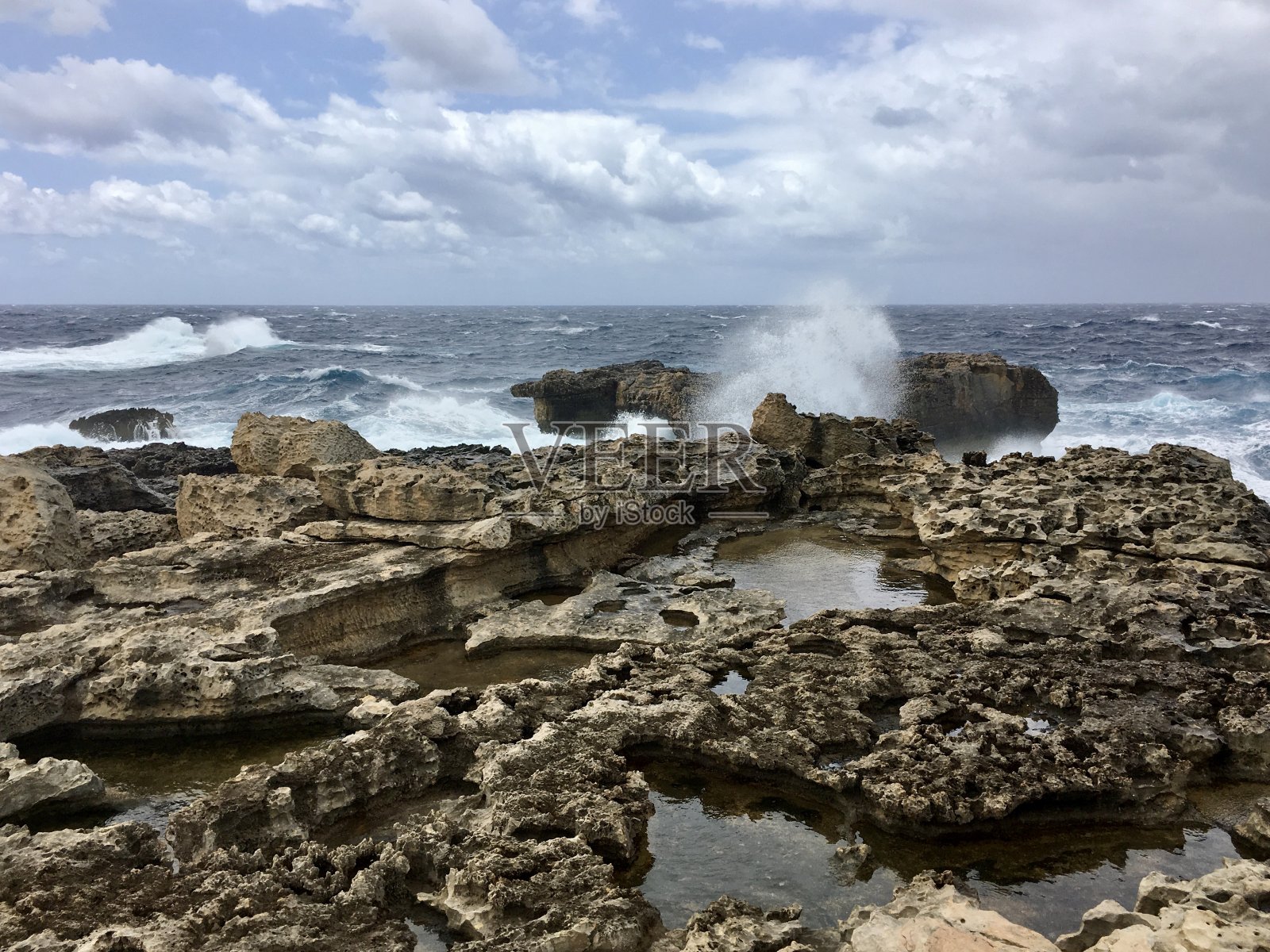 岩石海岸与多云的天空和海浪在海上照片摄影图片
