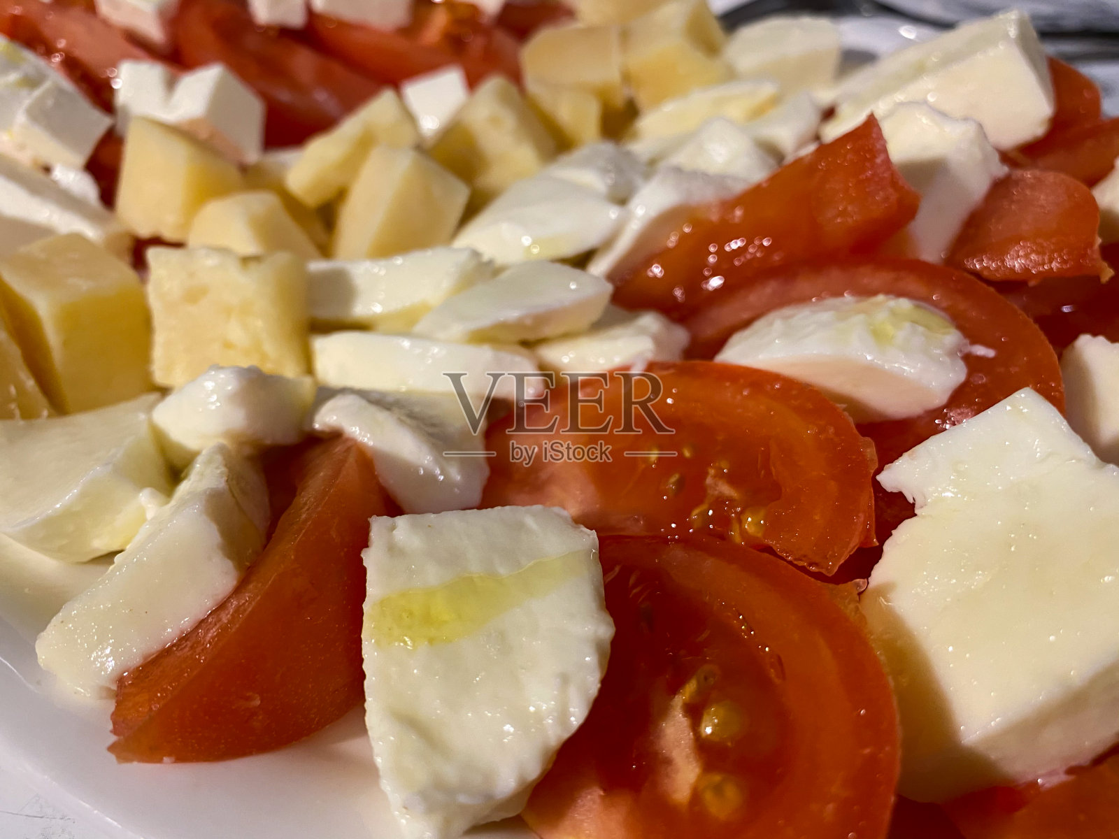 切成薄片的红番茄和羊乳酪，马苏里拉奶酪放在白色盘子里。健康的零食。照片摄影图片