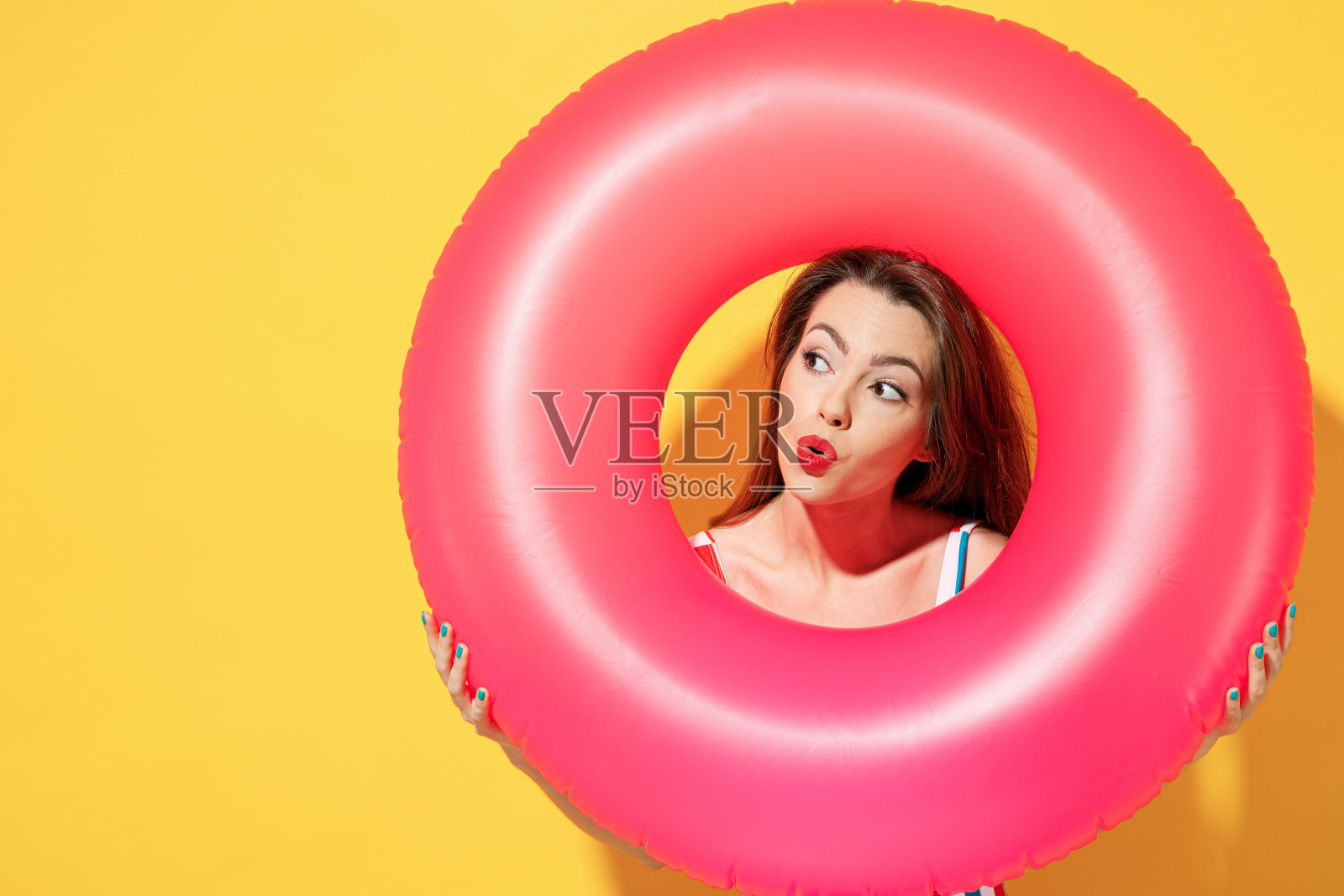 快乐乐趣年轻性感女人苗条的身体穿条纹红蓝色连体泳衣hold粉色充气环孤立在鲜艳的黄色背景工作室夏季酒店泳池海休息太阳晒黑的概念照片摄影图片