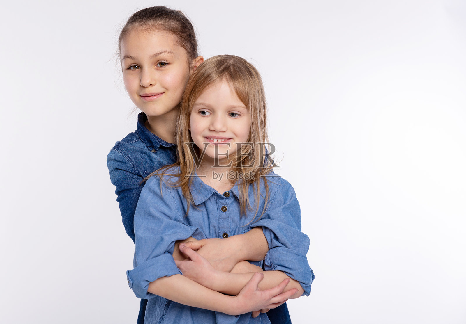 两个快乐的朋友或姐妹，小女孩拥抱着。一起有乐趣和摆情感的白色背景，快乐的微笑，友谊和关系的生活方式的人的概念照片摄影图片
