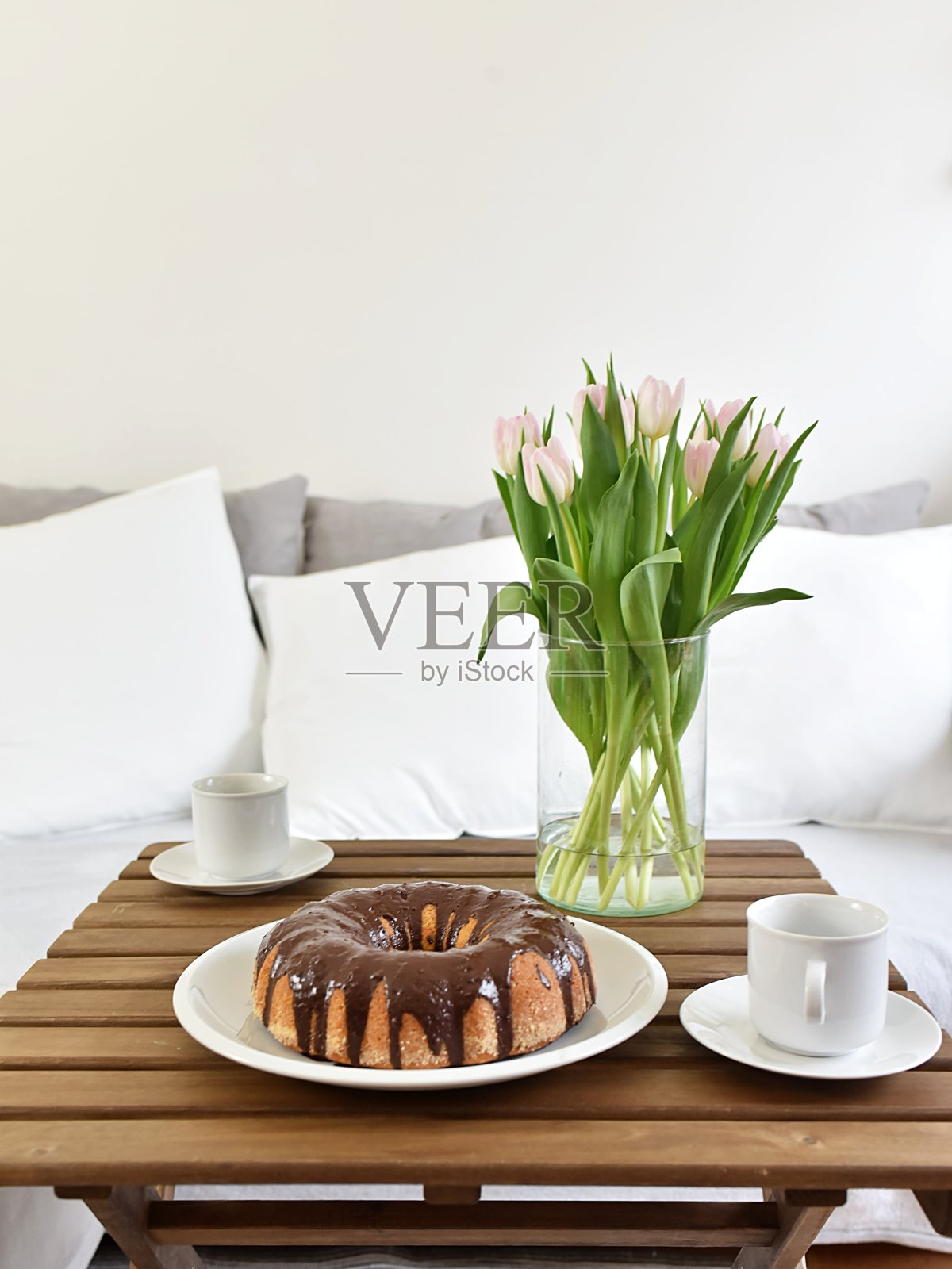 放在托盘上的自制蛋糕。花瓶里的粉色郁金香照片摄影图片
