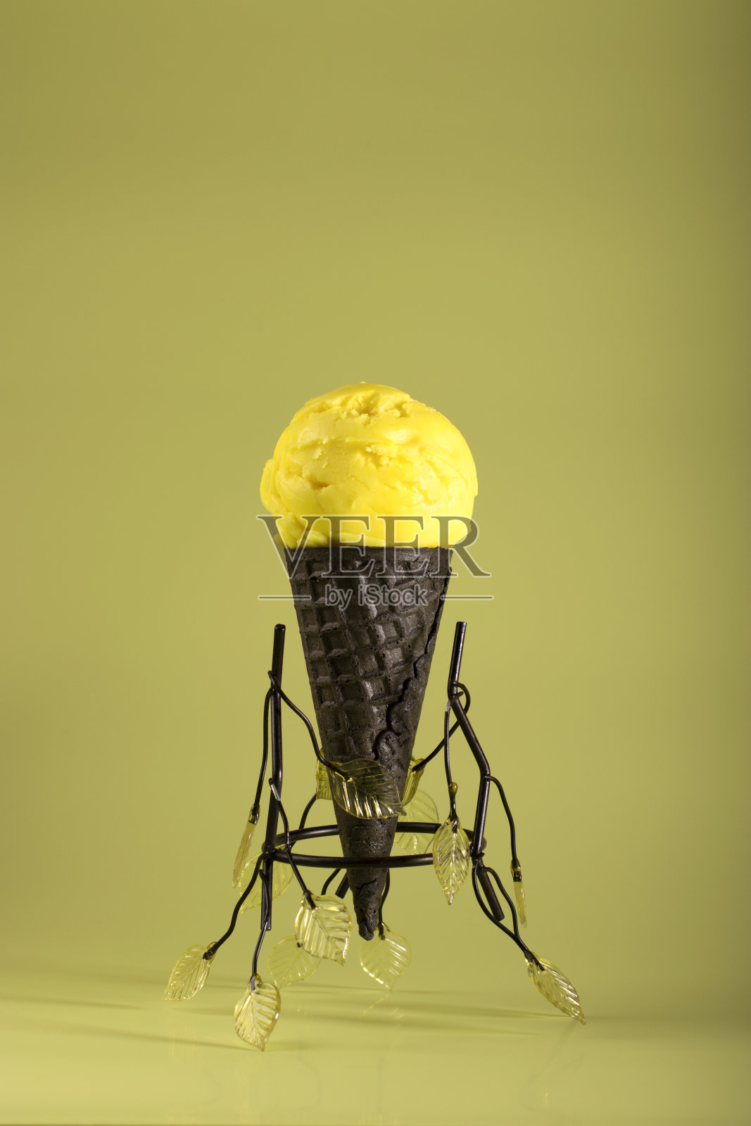 自制的黄色水果味冰淇淋，在深色华夫蛋筒里，在浅色的背景上。健康的天然食品。副本的空间。照片摄影图片