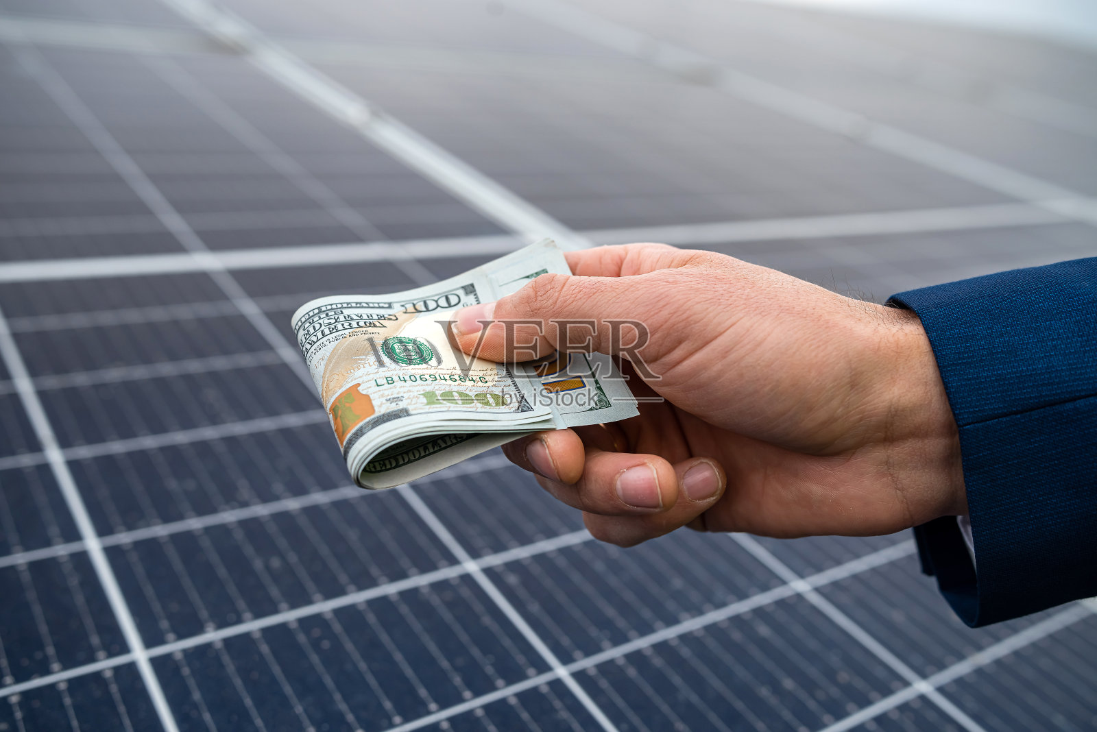 英俊的男性手握美元支付与太阳能电池板工作。照片摄影图片