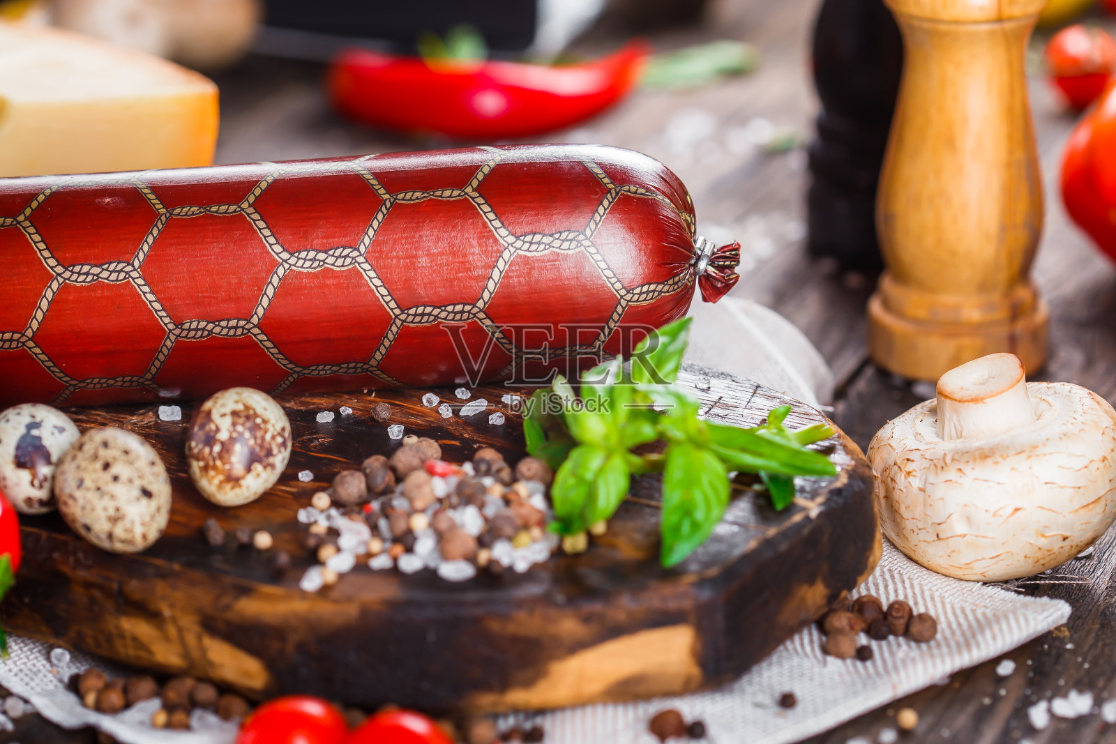 意大利腊肠配培根片，整块或切片，绿罗勒，樱桃番茄，奶酪和香料，厨房砧板，深色和忧郁，在黑色木制的孤立背景上，顶部照片摄影图片