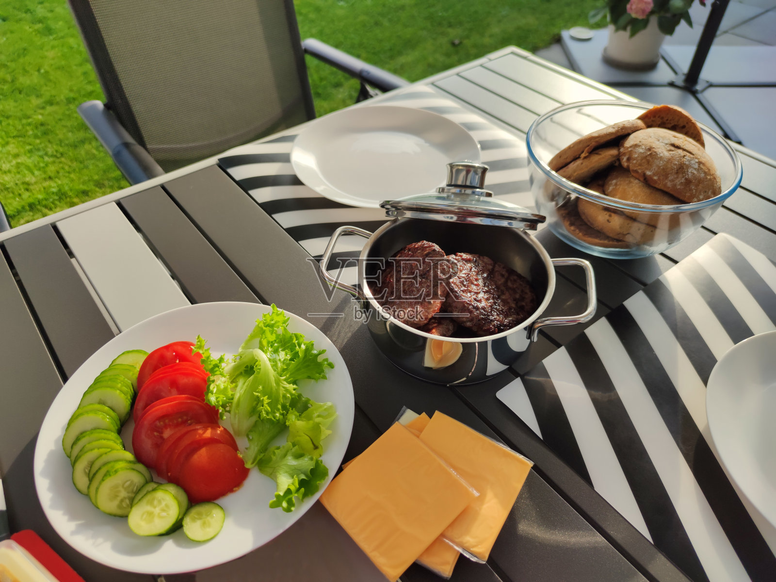 在夏日阳光明媚的日子里，舒适的后院摆满了烤汉堡、蔬菜和面包照片摄影图片