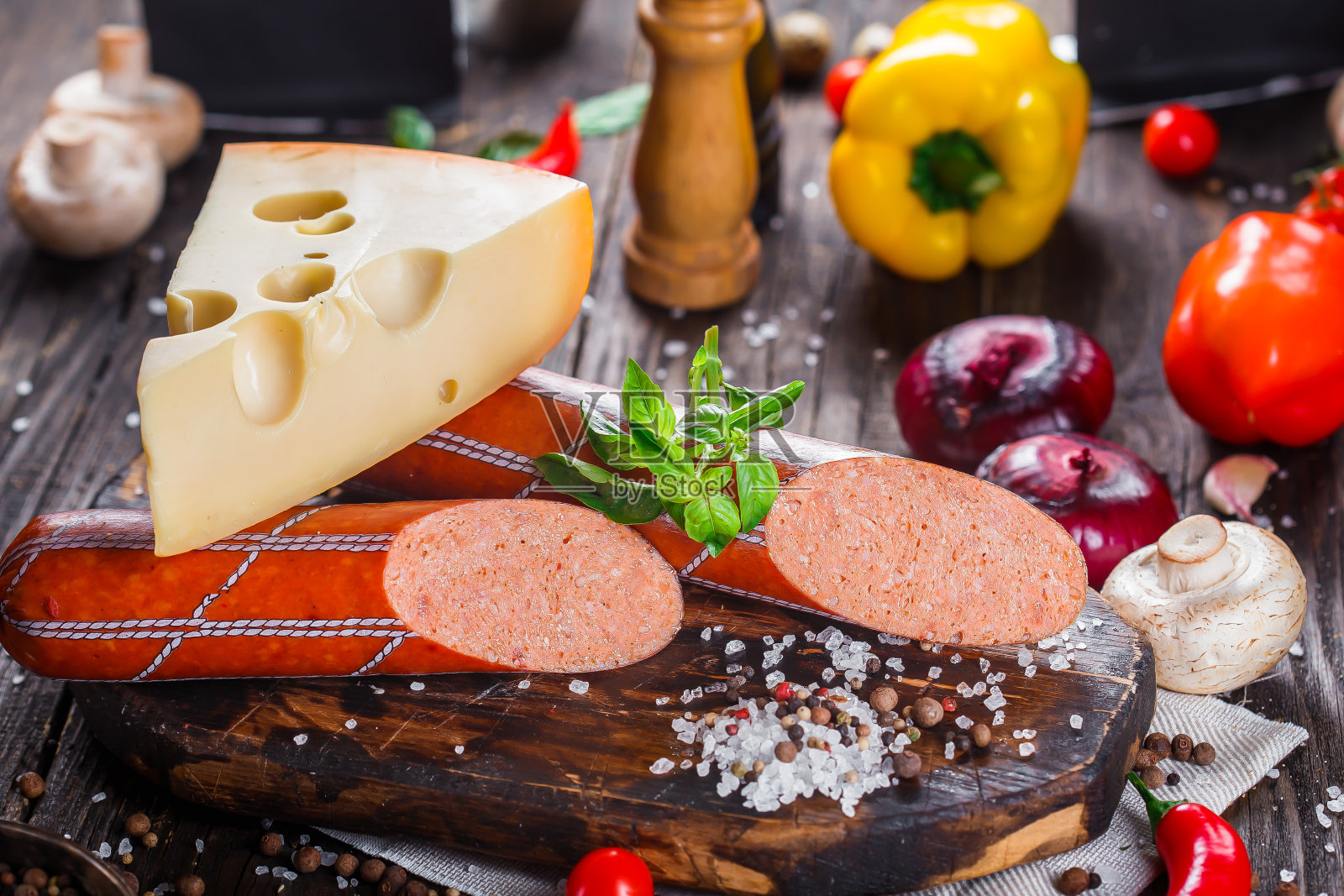 意大利腊肠配培根片，整块或切片，绿罗勒，樱桃番茄，奶酪和香料，厨房砧板，深色和忧郁，在黑色木制的孤立背景上，顶部照片摄影图片
