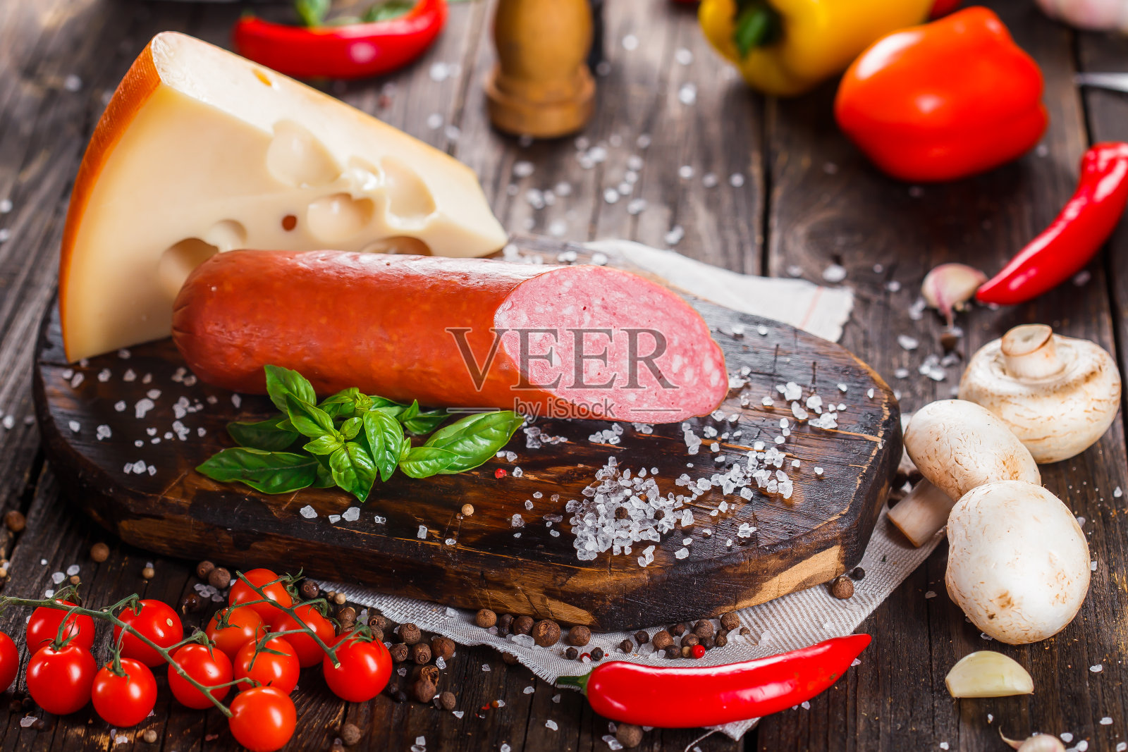 意大利腊肠配培根片，整块或切片，绿罗勒，樱桃番茄，奶酪和香料，厨房砧板，深色和忧郁，在黑色木制的孤立背景上，顶部照片摄影图片