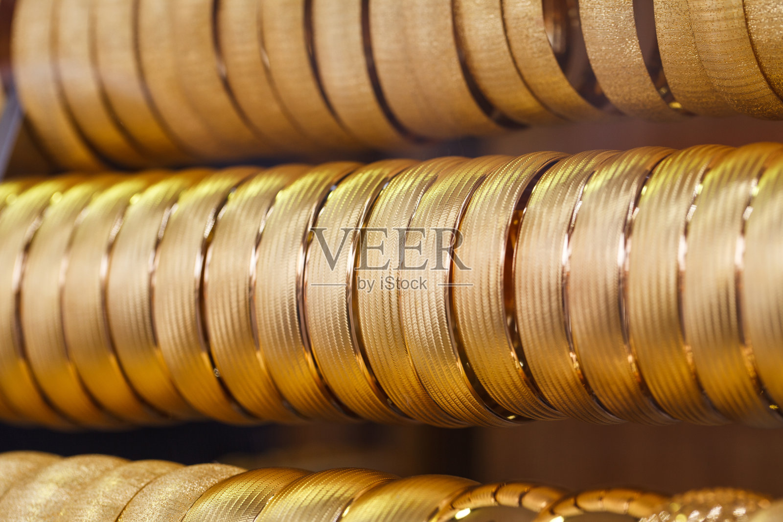 土耳其集市上，一排一排地挂着金手镯。照片摄影图片