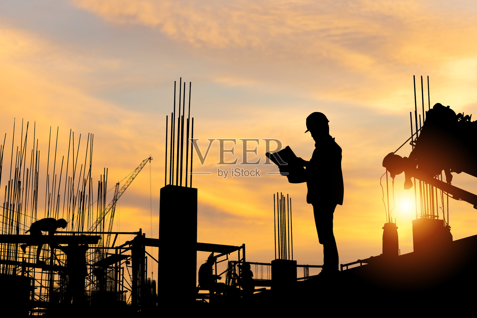 工程师和工人在建筑工地检查工程的剪影，傍晚时分在建筑工地夕阳下的工人队伍照片摄影图片
