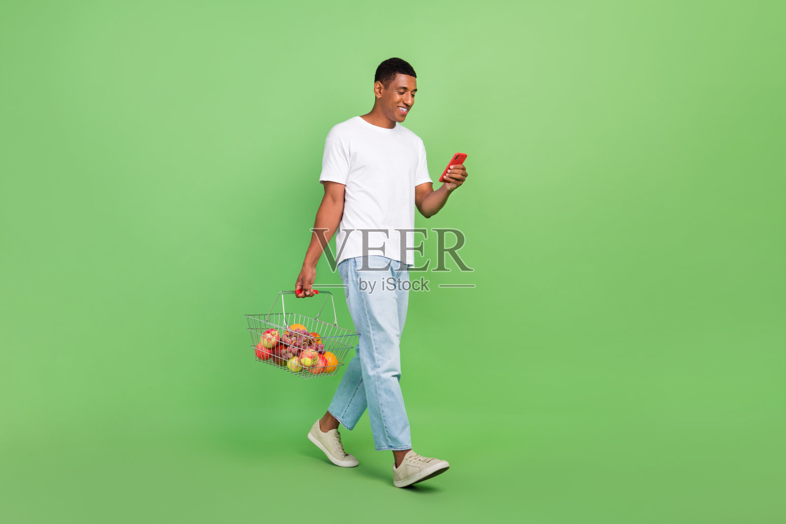 全尺寸的侧面照片年轻的非洲人类型浏览手机购物中心孤立在绿色的背景照片摄影图片