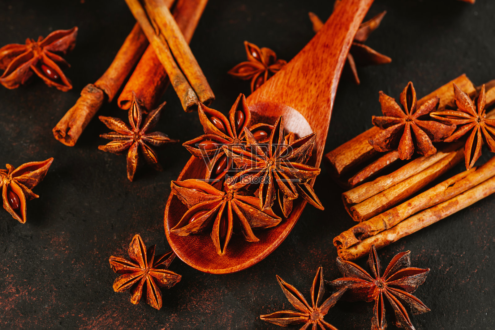 加香料的热葡萄酒。圣诞节、寒假、新年的概念。圣诞家居装饰。新年贺卡的背景。肉桂棒配八角茴香和橙子干，为秋冬暖饮做准备，背景为黑色。照片摄影图片