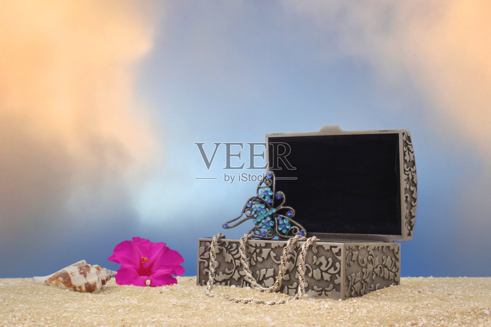 首饰盒和沙滩上的花，蓝天为背景照片摄影图片