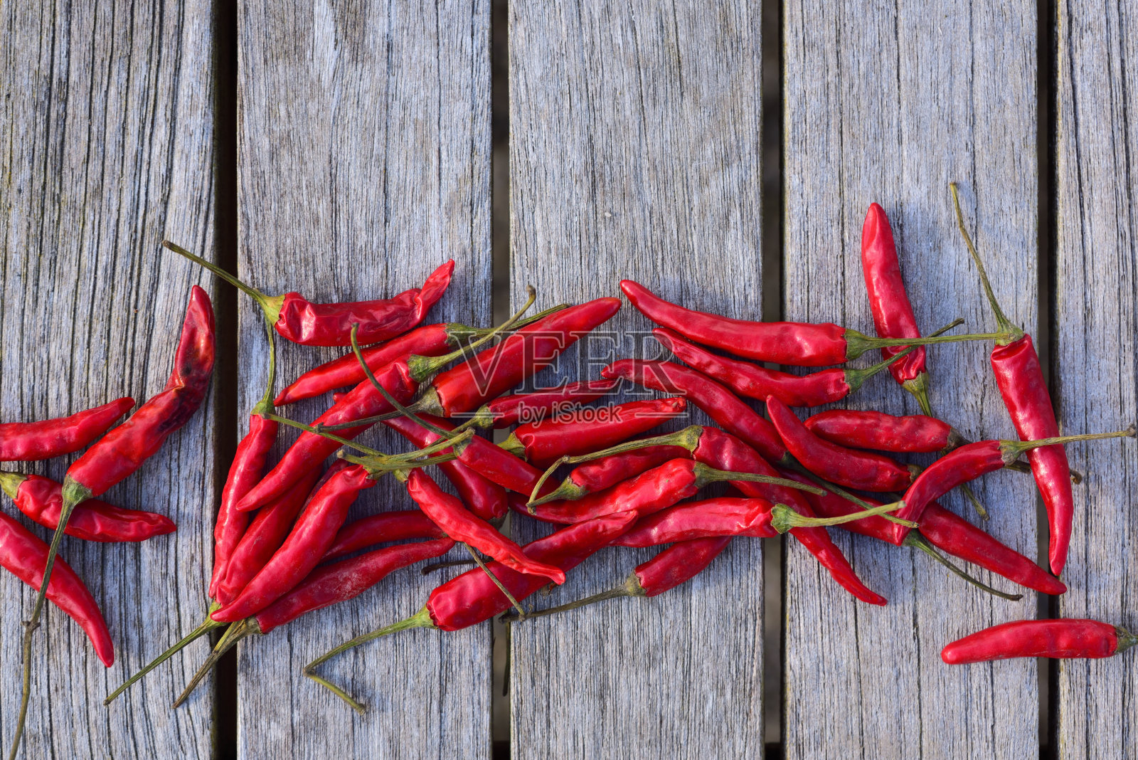 红色的小辣椒并排躺在木制背景前。木材构成文字的背景照片摄影图片