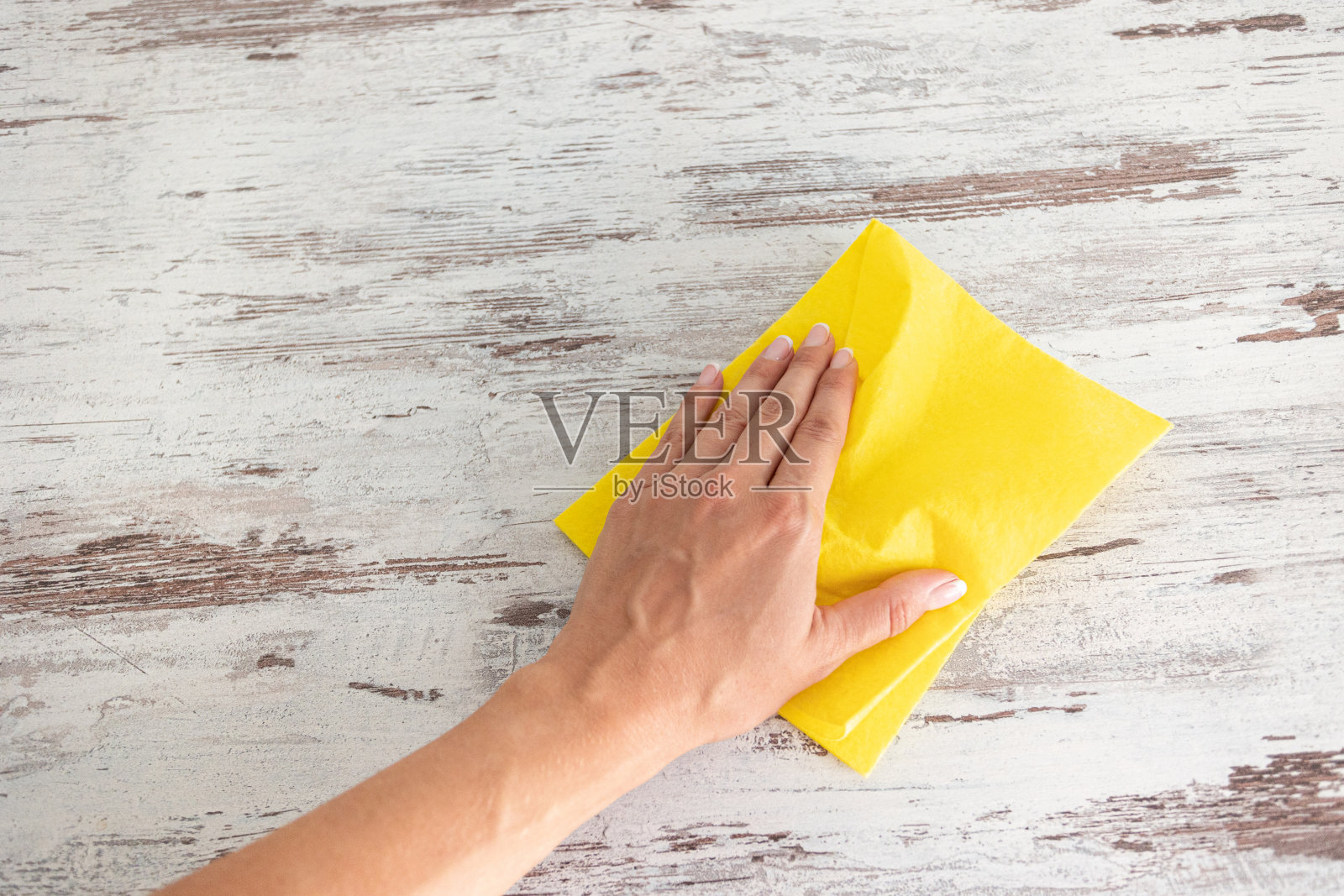 在一个女人手上擦黄色的餐巾。清洁服务。消毒的概念。抵御病毒和细菌照片摄影图片