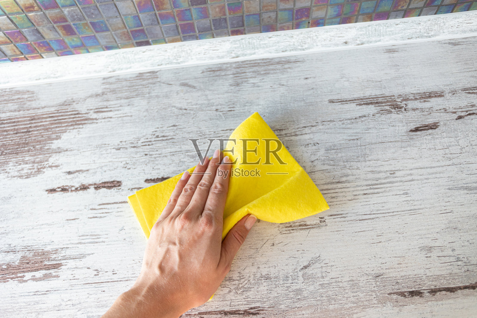 在一个女人手上擦黄色的餐巾。清洁服务。消毒的概念。抵御病毒和细菌照片摄影图片