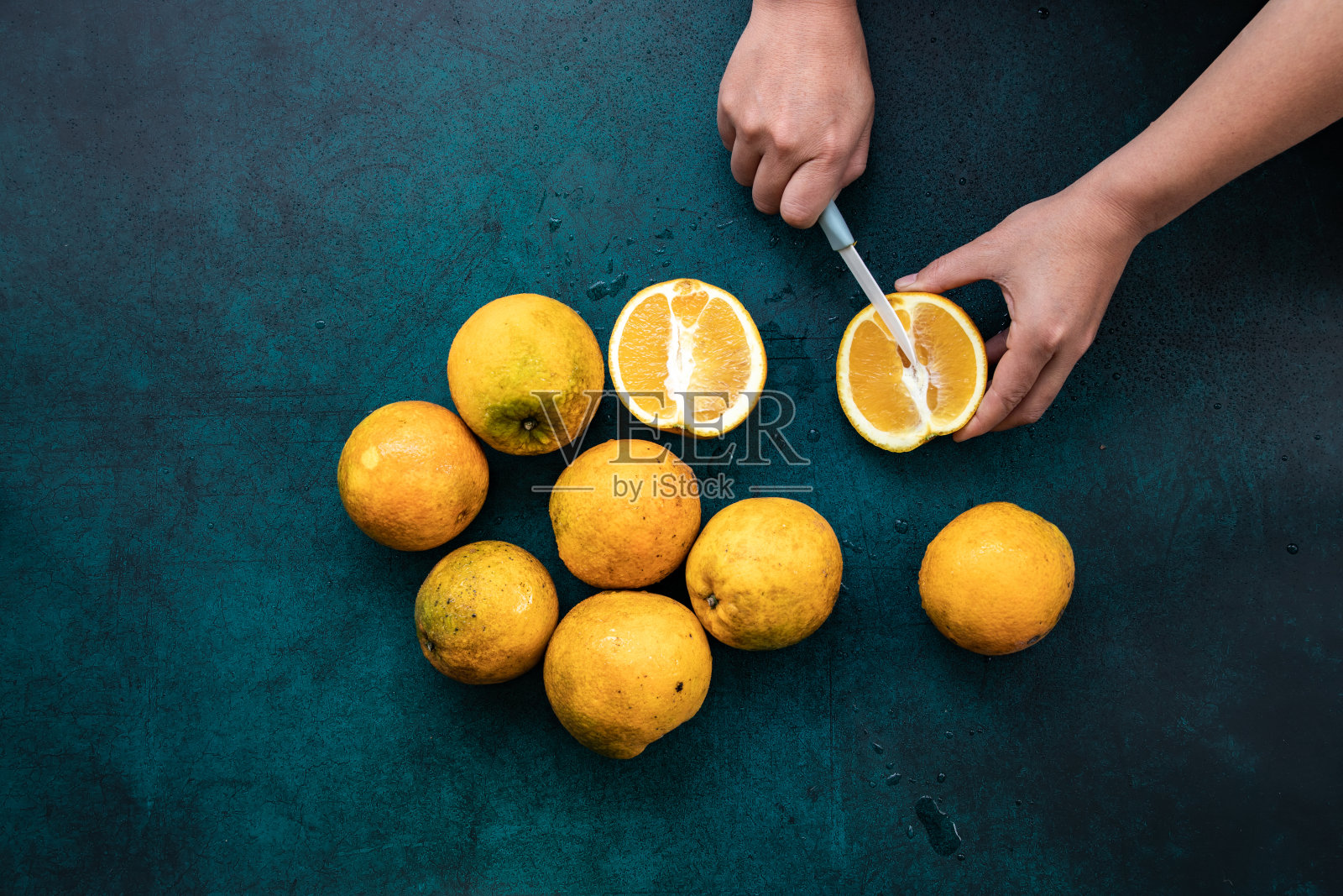 女人的手拿着一个新鲜的有机橙，背景是深绿色的。照片摄影图片