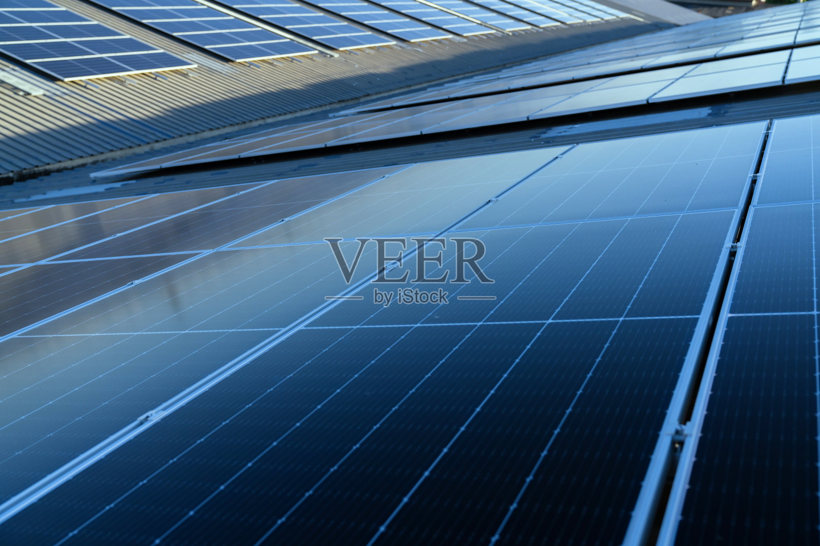 太阳能电池替代能源安装在工厂的屋顶太阳能电池板和发电站，近距离观察一个大型建筑的屋顶太阳能电池板。照片摄影图片